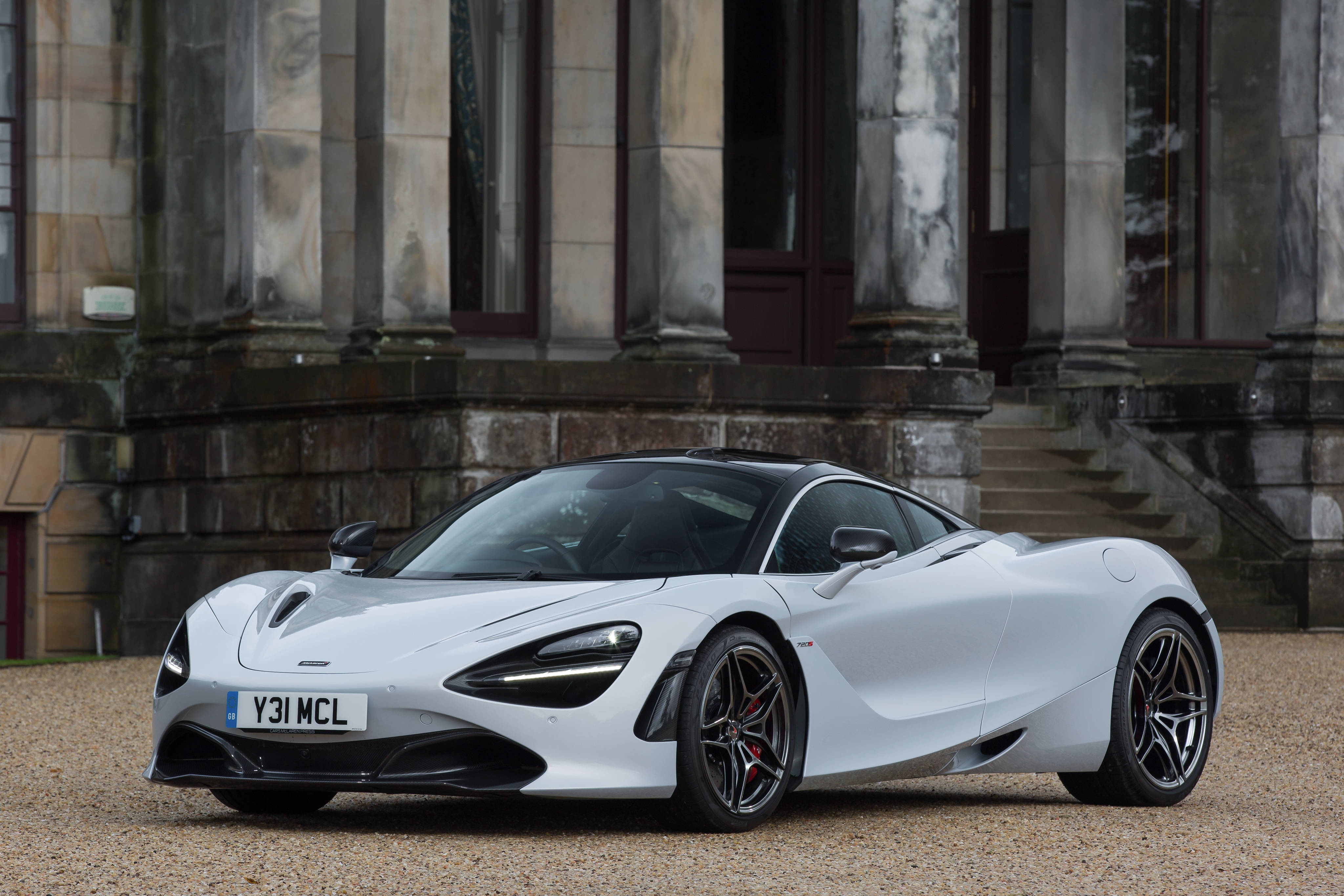 停靠於石砌建築前的奢華麥拉倫720S 壁紙 — 一架時尚的白色McLaren 720S跑車停泊在碎石上，前方是一座帶有柱子的宏偉石建築。