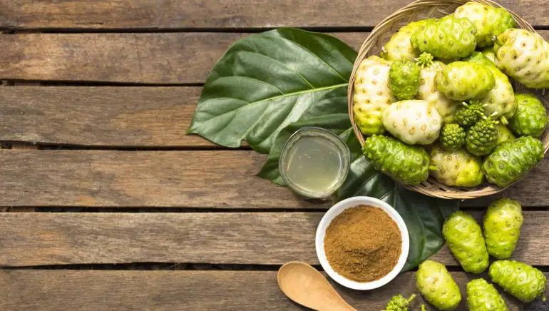 一籃諾麗果，附有粉末和果汁，置於木質表面。