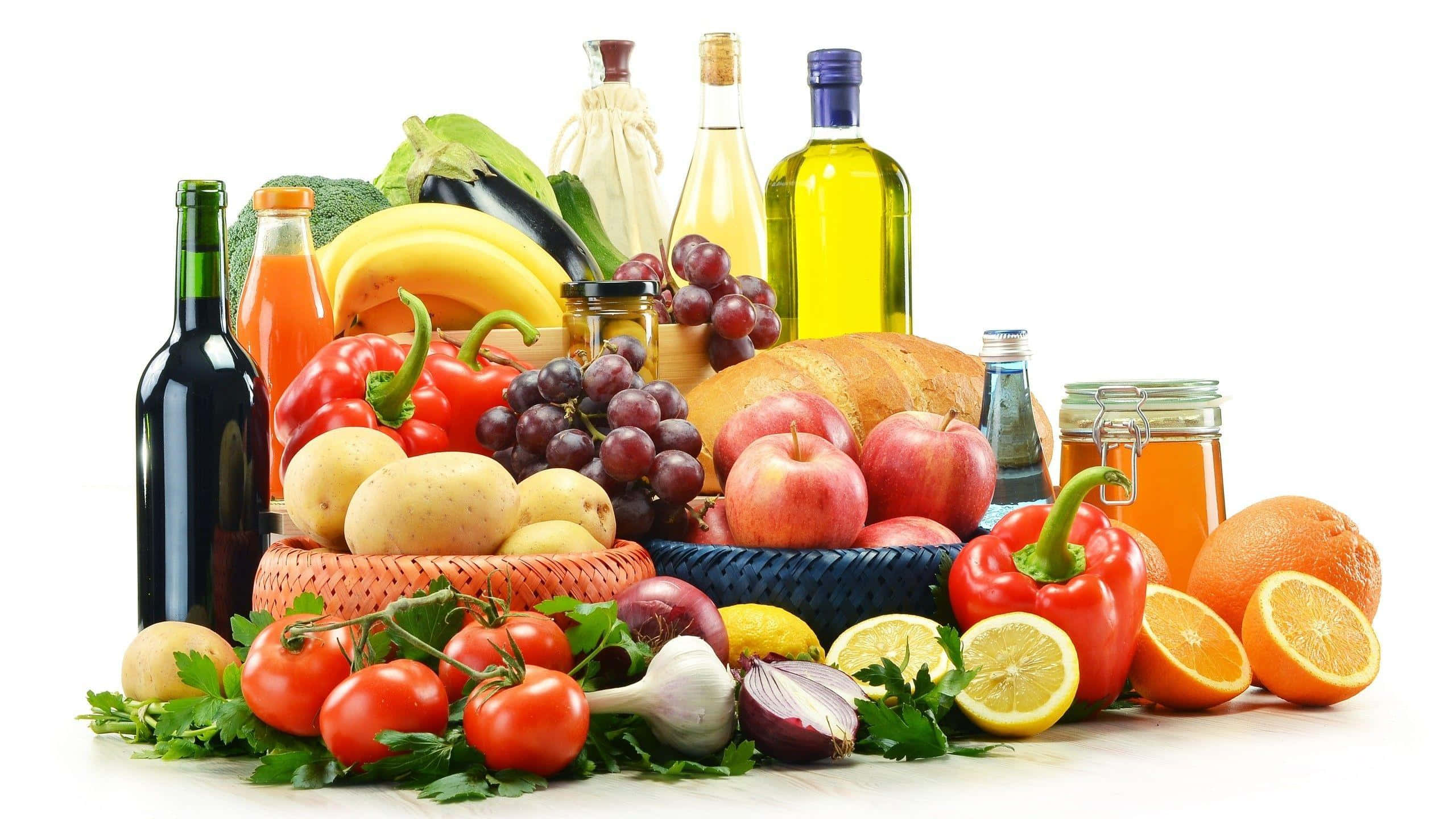 健康烹調食材 壁紙 — 一個充滿活力的靜物畫，新鮮水果、蔬菜、油和麵包整齊地擺放在籃子裡，背景是乾淨的白色。
