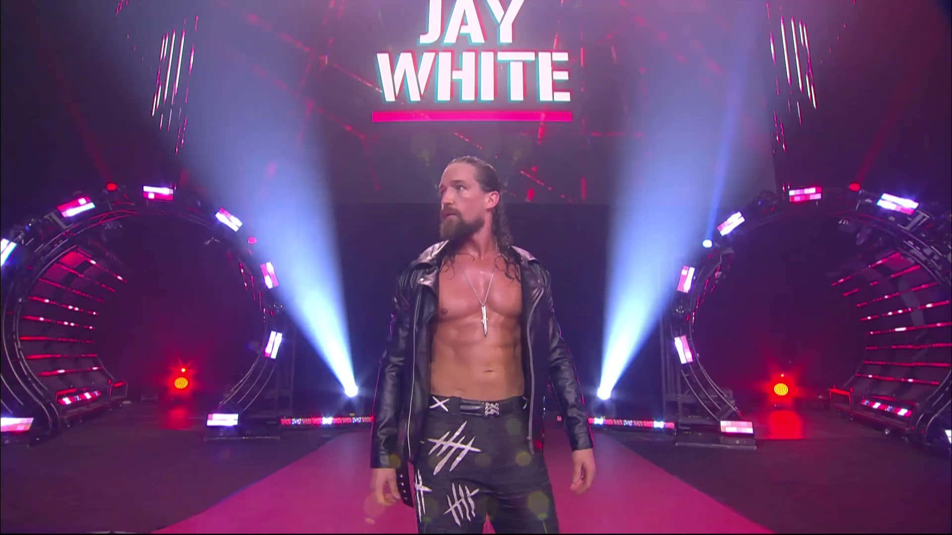 傑·懷特於AEW Rampage賽事登場 壁紙 — 摔角手 Jay White 在戲劇性的藍色和紅色舞台燈光下自信地走過紅地毯。