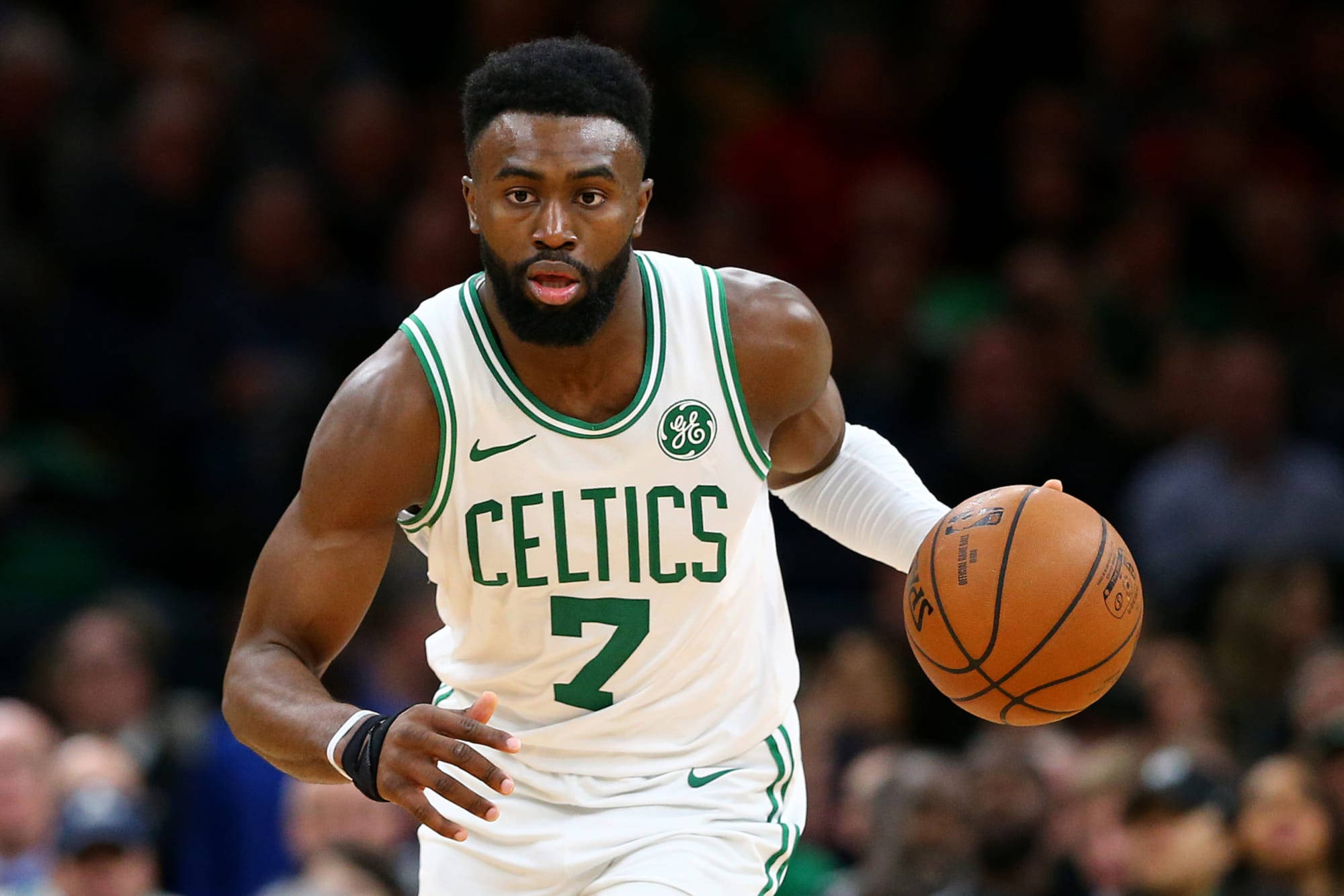 傑倫·布朗NBA凱爾特人 壁紙 — 一位身穿白色和綠色球衣的波士頓塞爾特人籃球運動員在比賽中專注地運球。