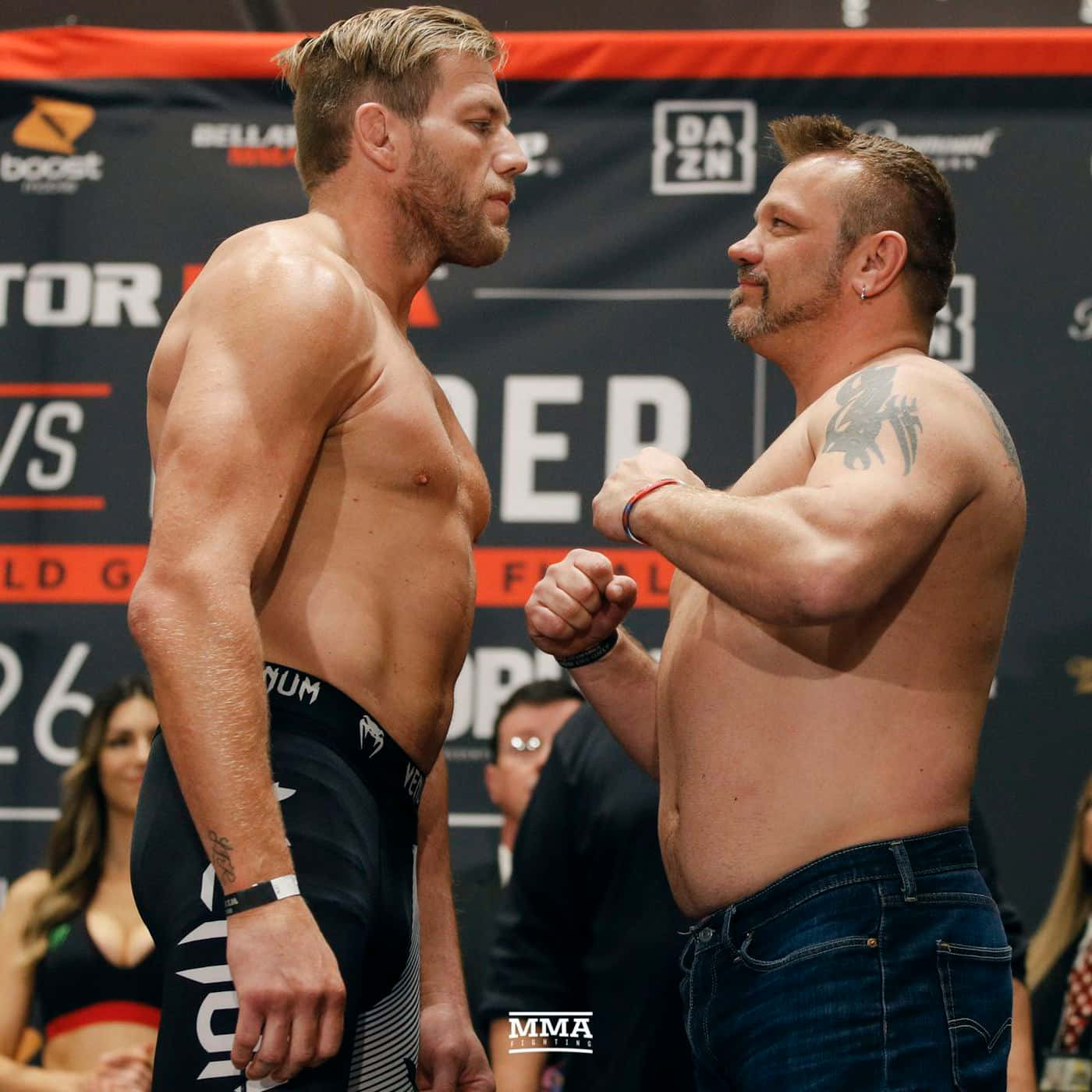 兩名赤裸上身的男性MMA拳手在稱重儀式中握拳對峙，氣氛緊張。