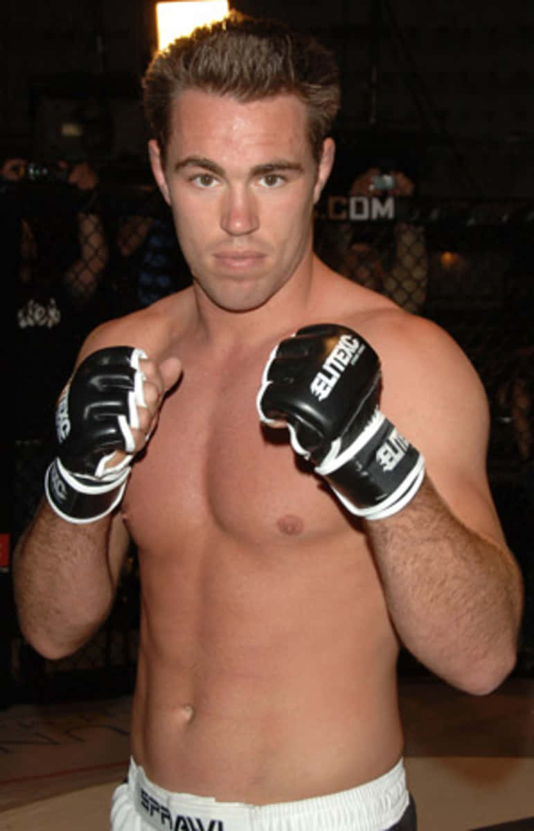男性MMA拳手戴著黑色手套在籠內擺姿勢。