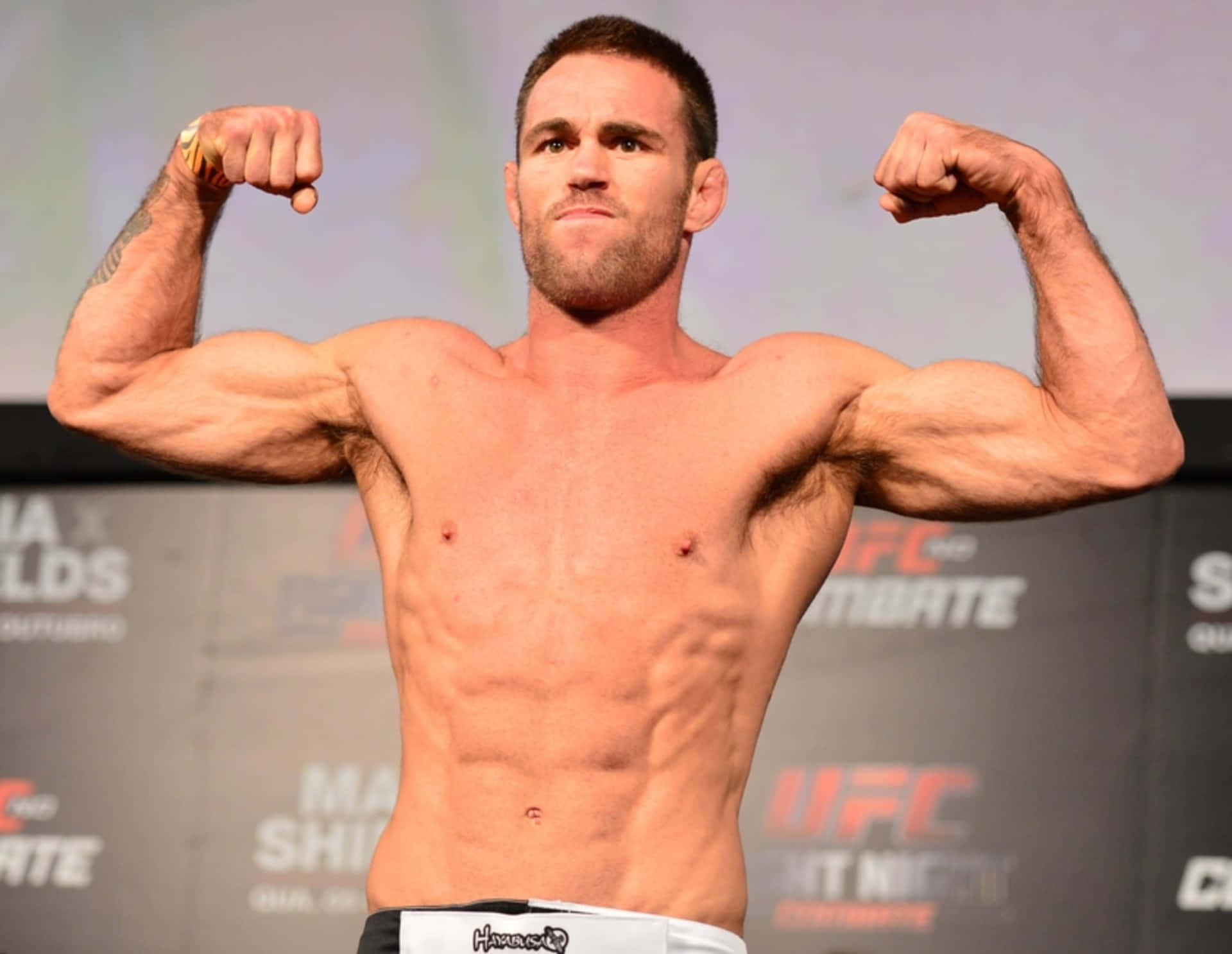 赤裸上身的 UFC 拳手在稱重活動中彎曲手臂。