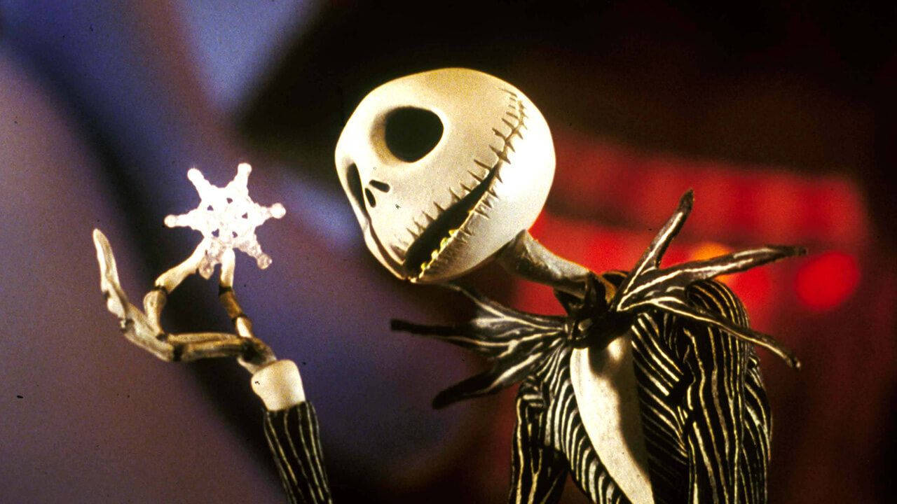 Jack Skellington 喺黑暗嘅節日場景中拎住一個發光嘅雪花。