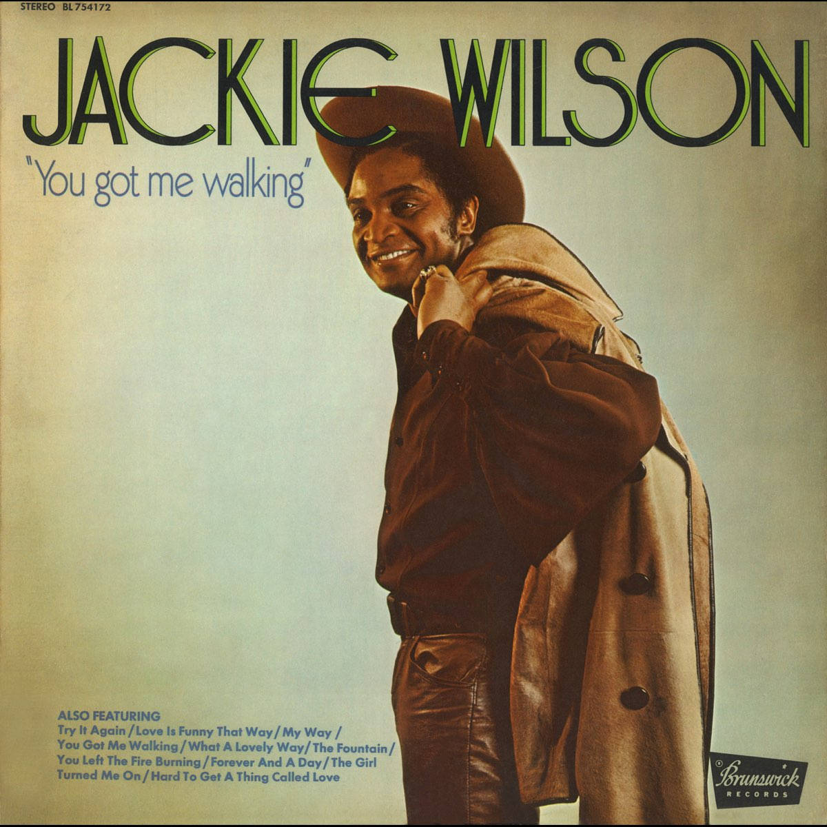 傑基·威爾遜美國歌手復古風情 壁紙 — Jackie Wilson 戴著棕色帽子和外套，在柔和的漸變背景前溫暖微笑，出現在他的《You Got Me Walking》專輯封面上。
