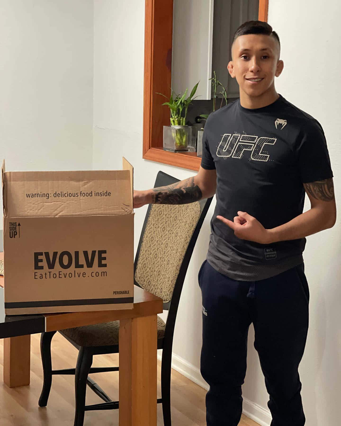 身穿UFC襯衫的男子手持標有Evolve的盒子，附有食物警告。