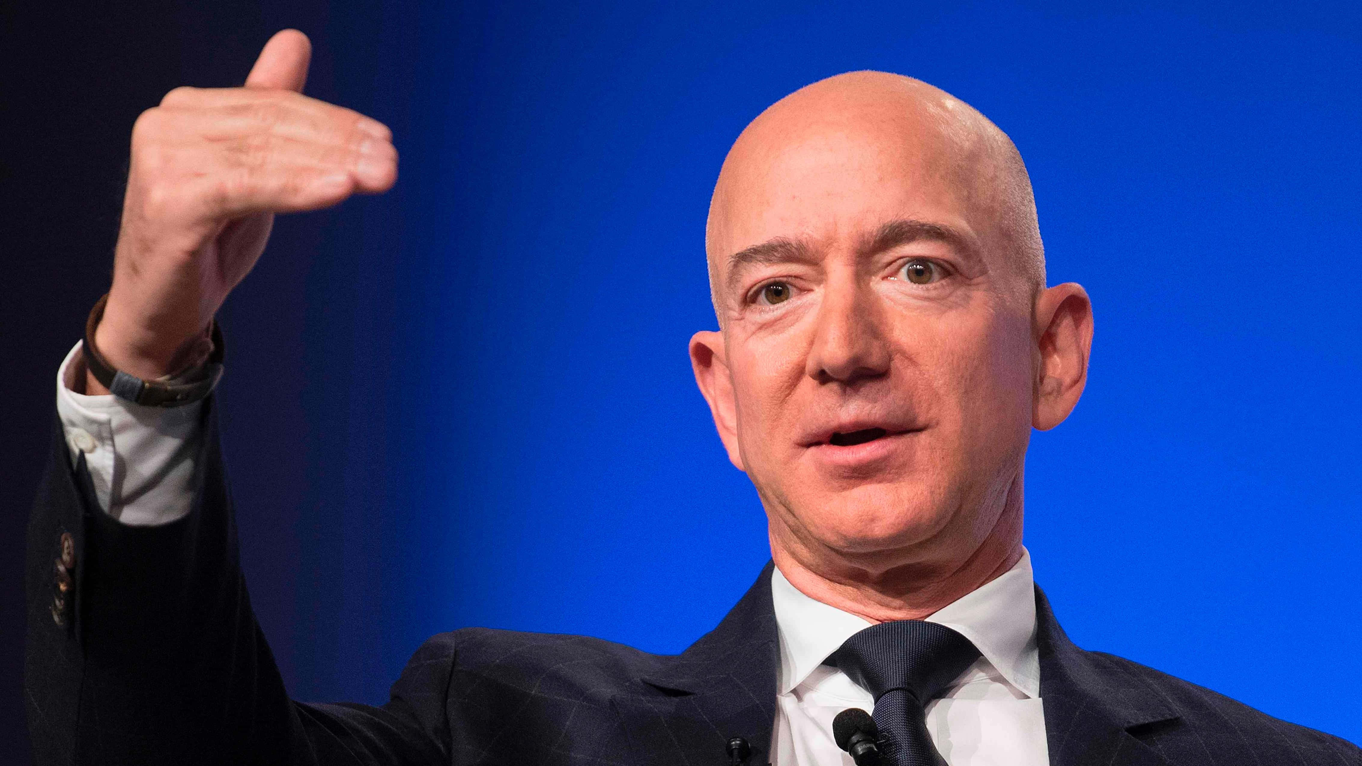 Jeff Bezos 桌布 壁紙 — 傑夫·貝索斯在純藍色背景的正式活動中發言並做手勢。