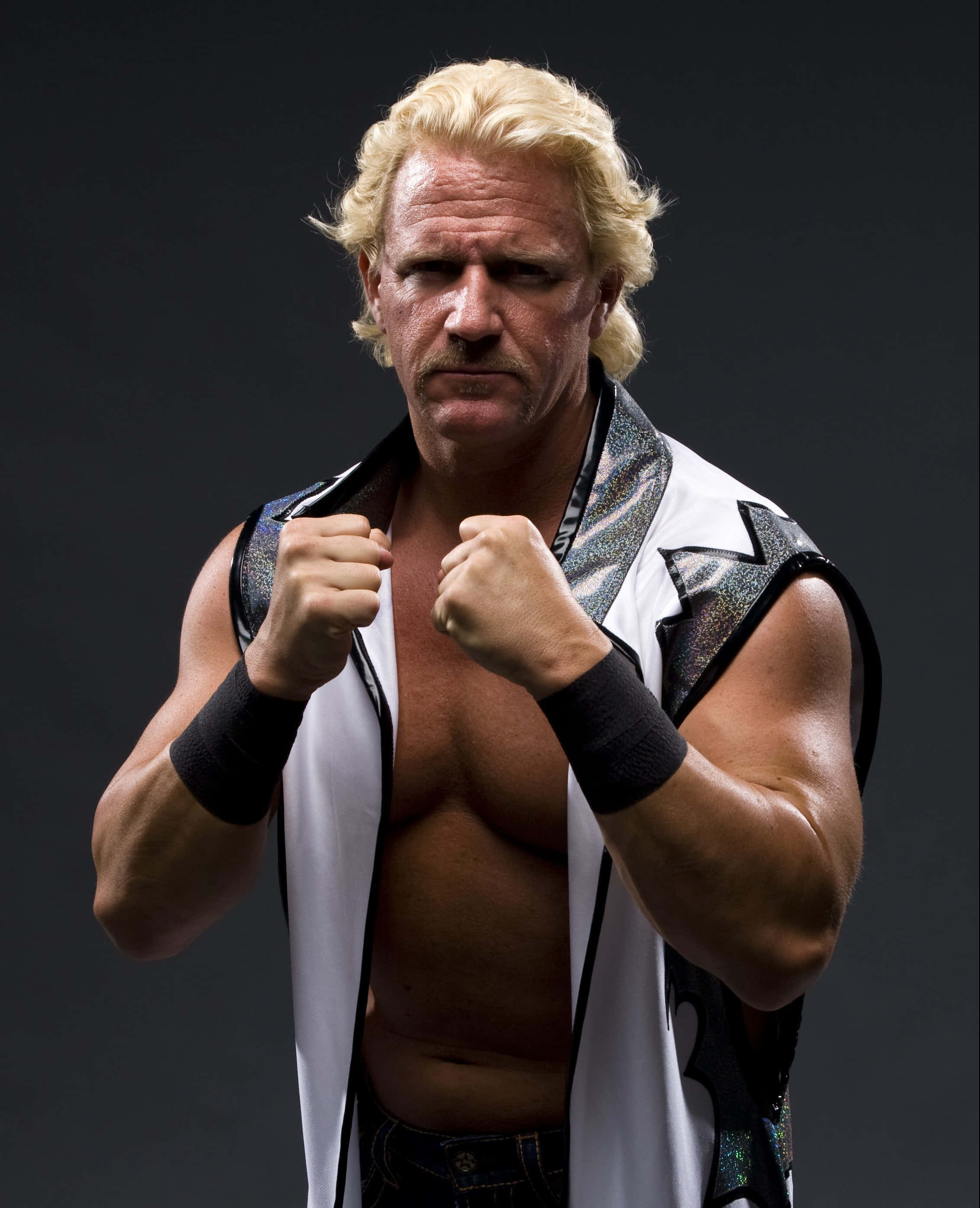 傑夫·賈雷特 WWE 職業摔角手攝影 壁紙 — 一位肌肉發達、金髮留鬚的摔角手，在黑暗背景下握緊拳頭擺姿勢。