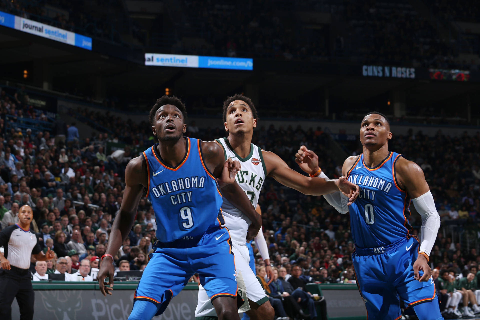 三名籃球運動員在NBA比賽中，背景有觀眾，正在進行動作。