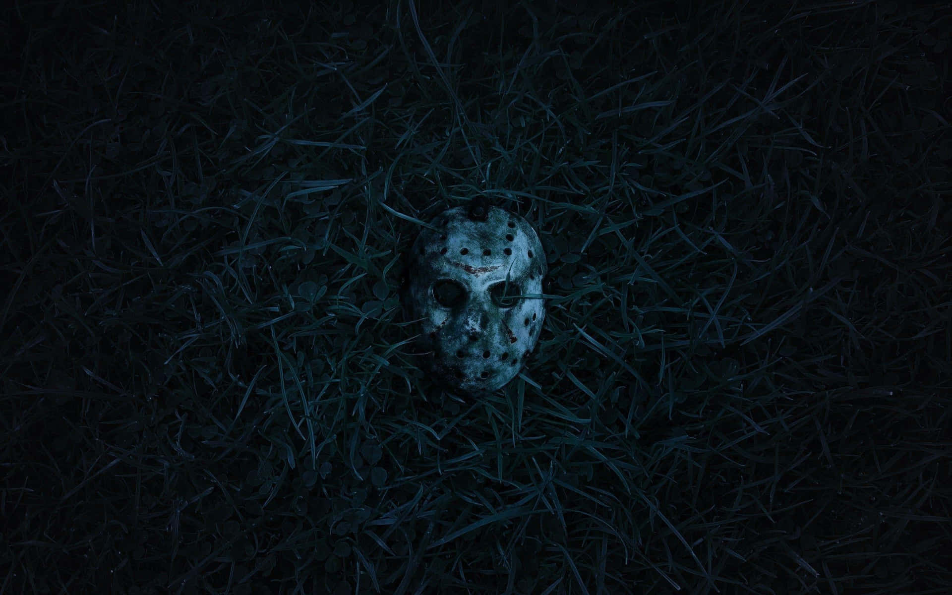 一個曲棍球面具在藍光下躺在黑暗的草地上，喚起恐怖。 — 傑森·沃赫斯 壁紙