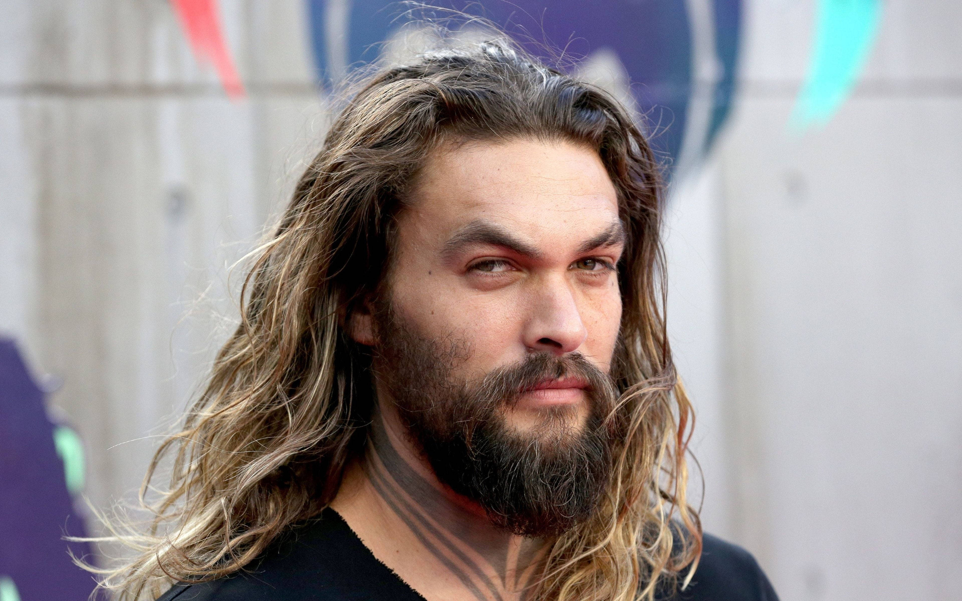 傑森·莫莫亞長髮 壁紙 — 演員積遜莫瑪（Jason Momoa）留著長捲髮和鬍鬚，專注地凝視著色彩繽紛的塗鴉牆。