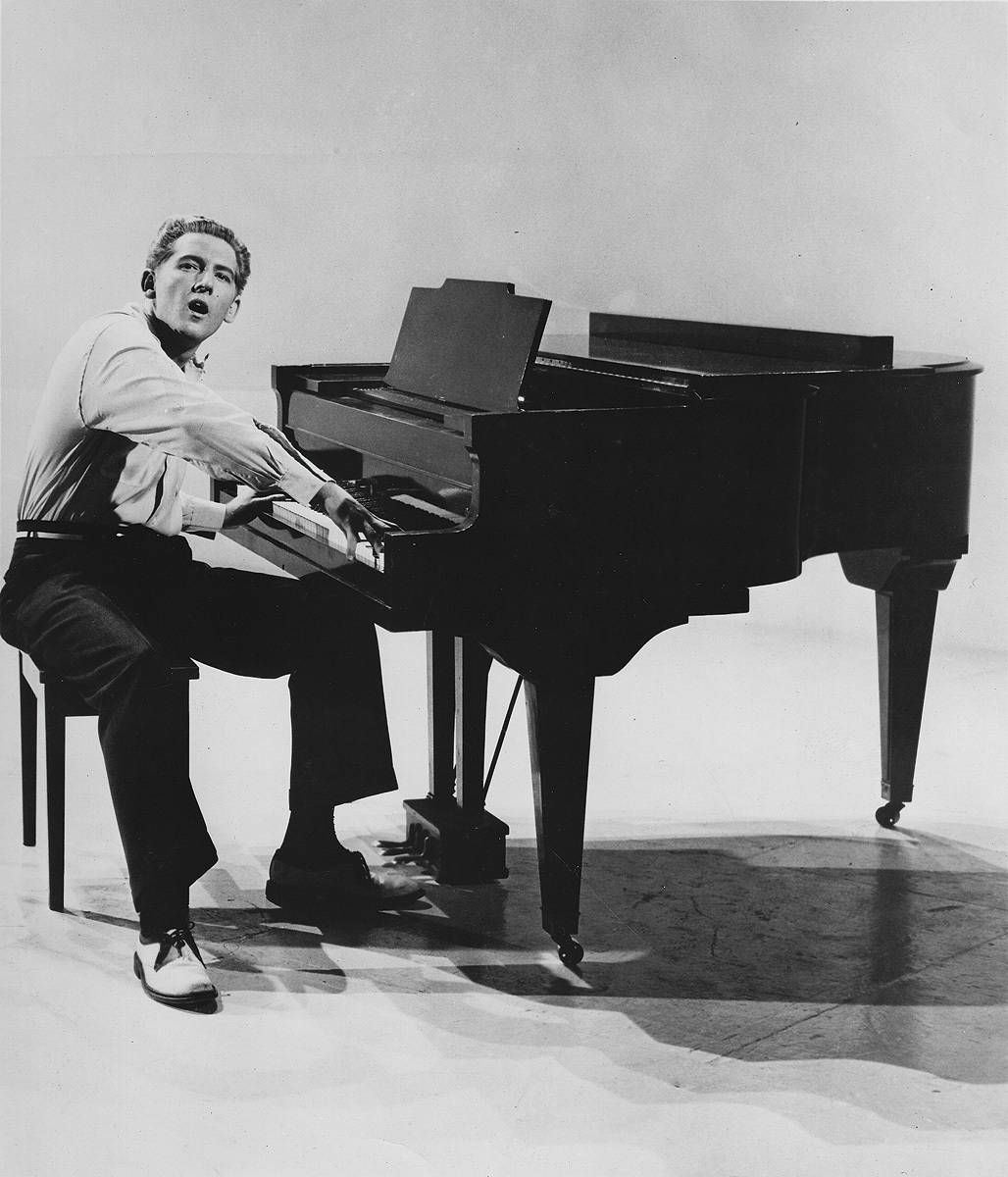 男子在黑白攝影棚唱歌彈奏三角鋼琴