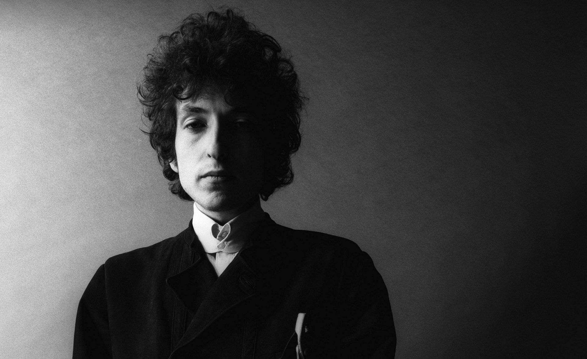 Bob Dylan 的黑白工作室肖像，捲髮，穿著深色外套。