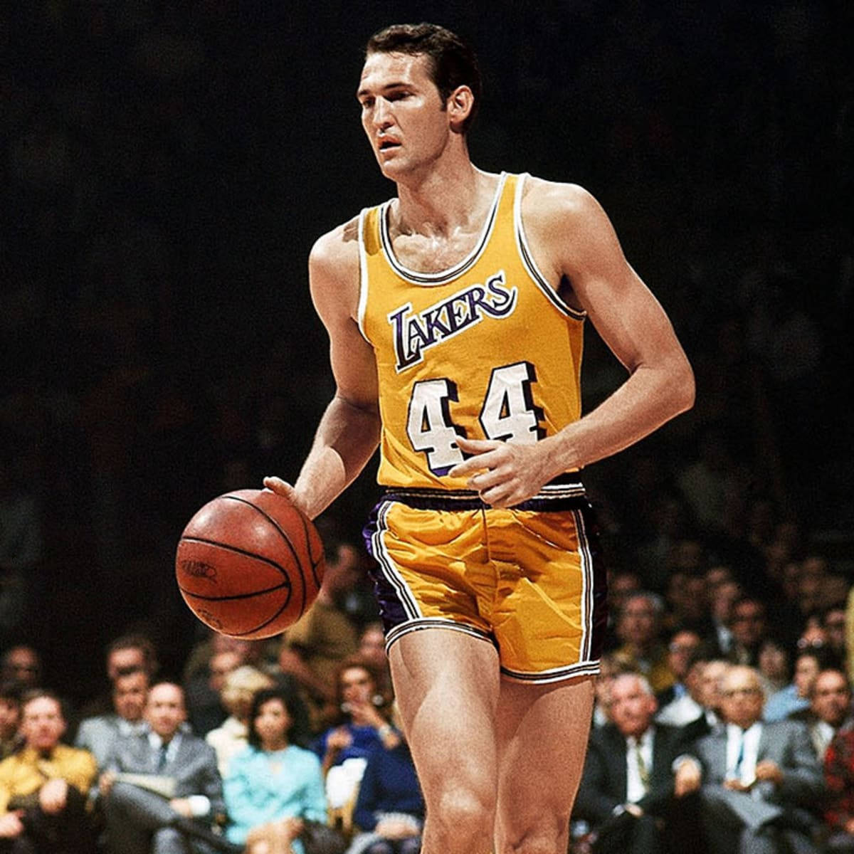 傑瑞·韋斯特 1969 NBA 總決賽 節奏運球 壁紙 — 一位身穿黃色湖人隊44號球衣的籃球運動員，在明亮的場館燈光下於比賽中運球。