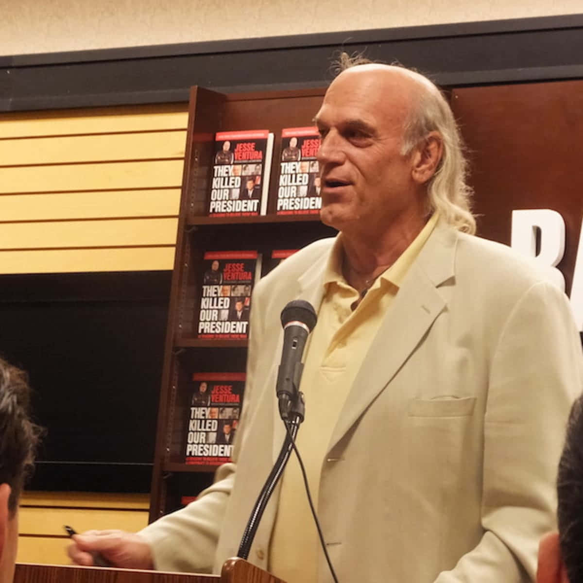傑西·文圖拉：前布魯克林公園市長 壁紙 — Jesse Ventura 在簽書會上發言，他的書《They Killed Our President》展示在他身後。