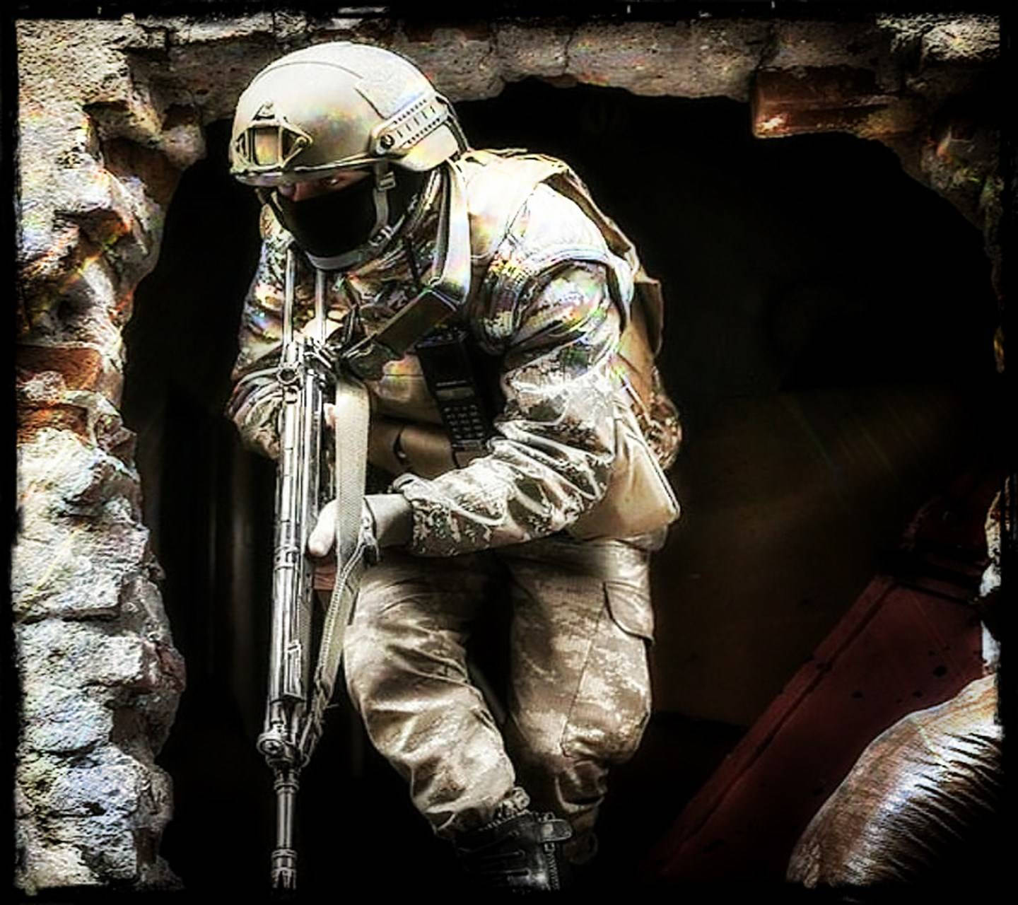 身穿戰鬥裝備的士兵在石拱門中持步槍蹲下。