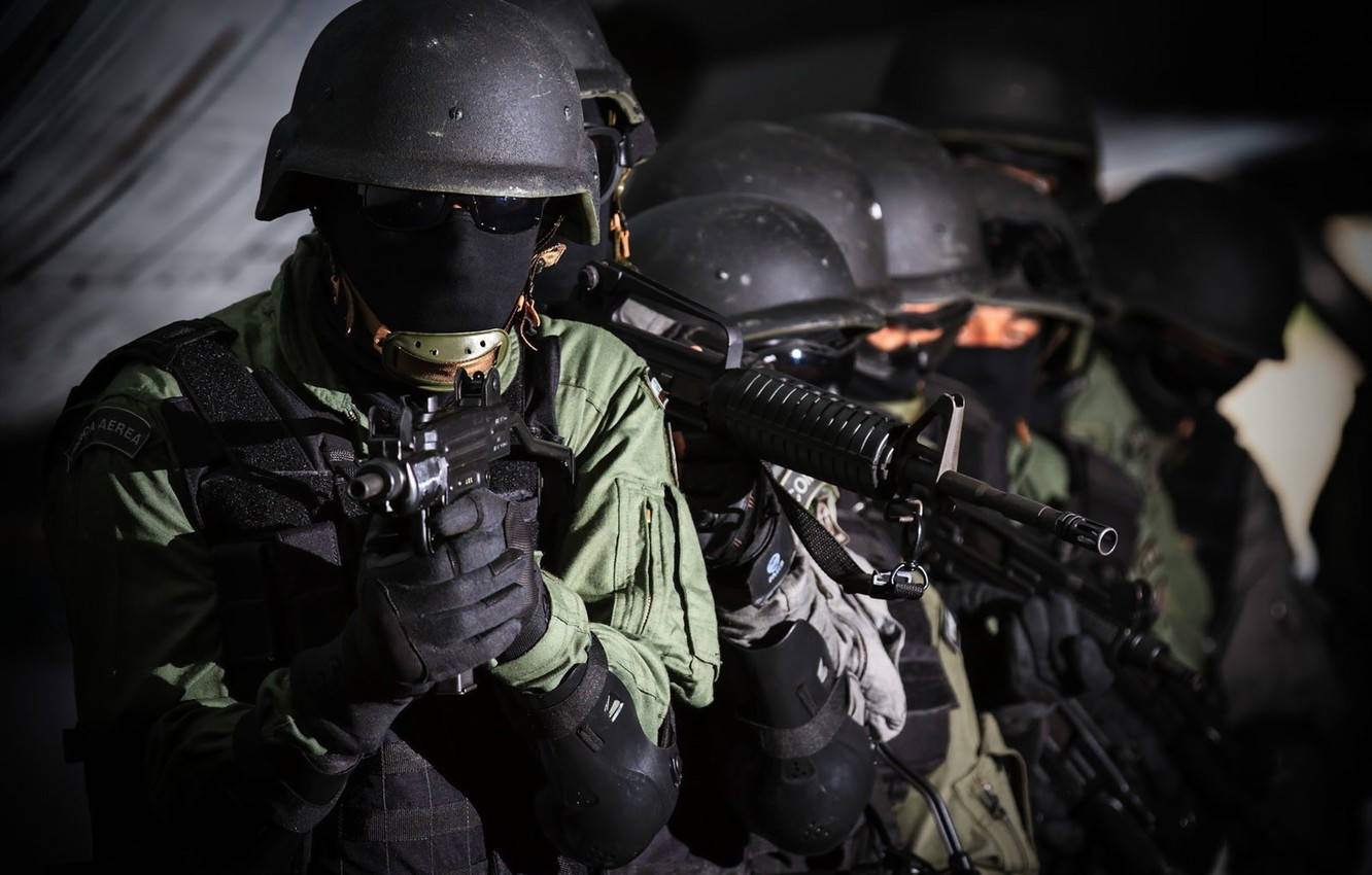 一排身穿戰術裝備的武裝士兵站在昏暗的光線中。