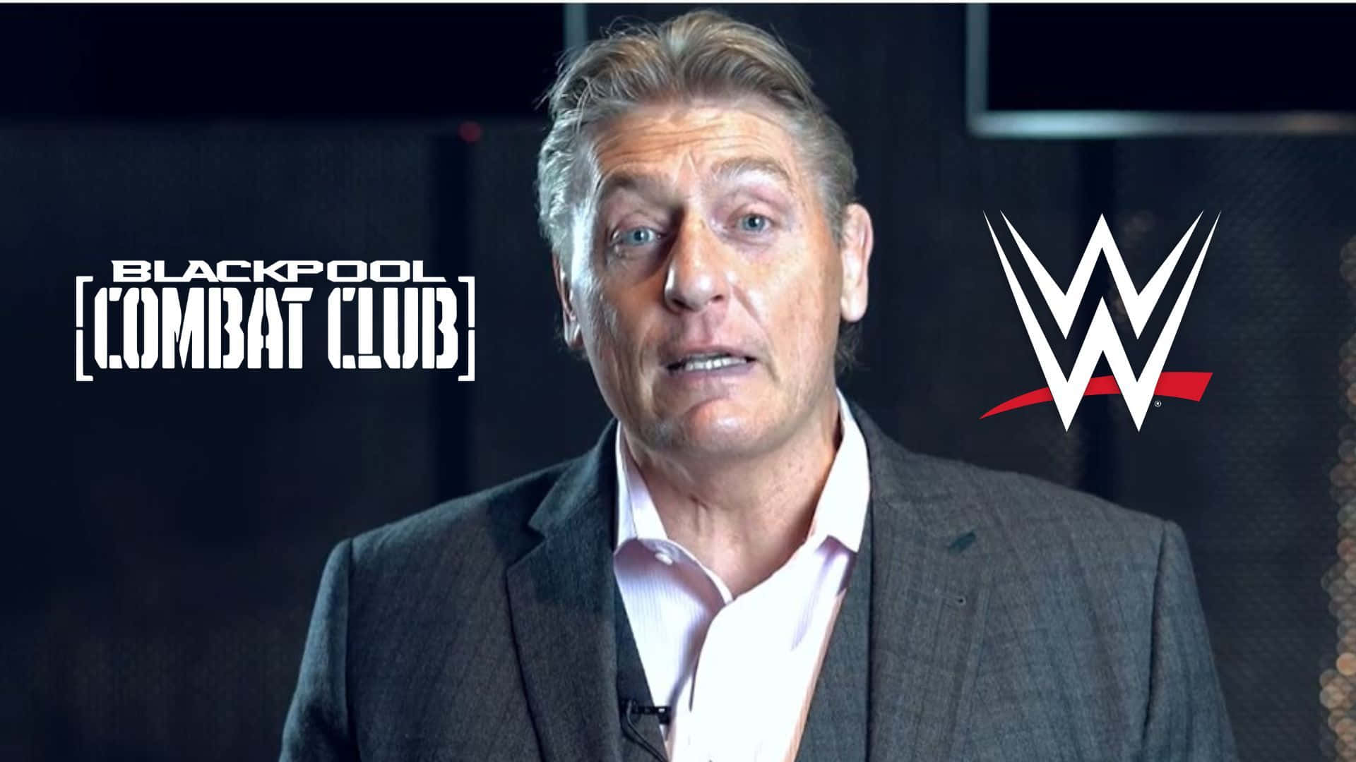 男子身穿西裝在WWE Blackpool Combat Club活動中發言。