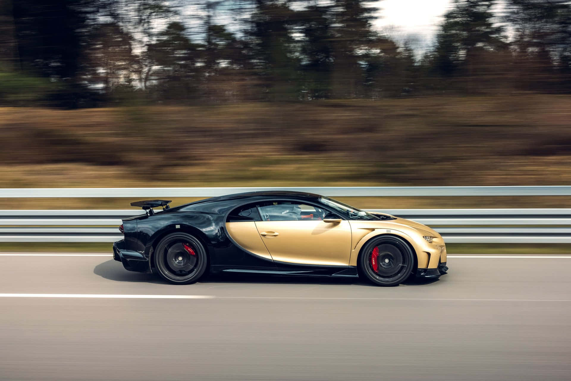 黑金色Bugatti在賽道上疾馳，背景樹木模糊。