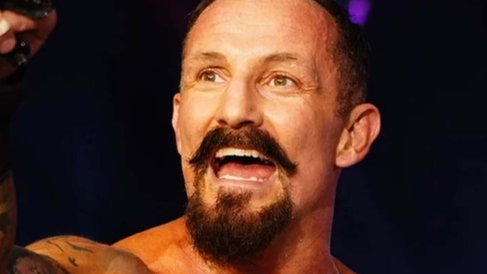 傳奇摔角手 Bobby Fish 壁紙 — 一個肌肉發達、留著濃密鬍鬚和鬍子的男人在舞台燈光下微笑著高舉獎盃。