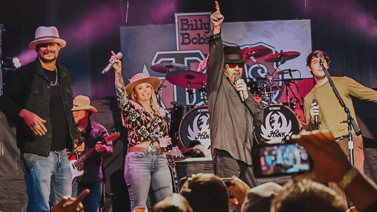 傳奇樂隊在沃斯堡演出 壁紙 — 一支充滿活力的鄉村樂隊在Billy Bob's Texas的舞台上表演，粉絲們歡呼並用手機捕捉這一刻。