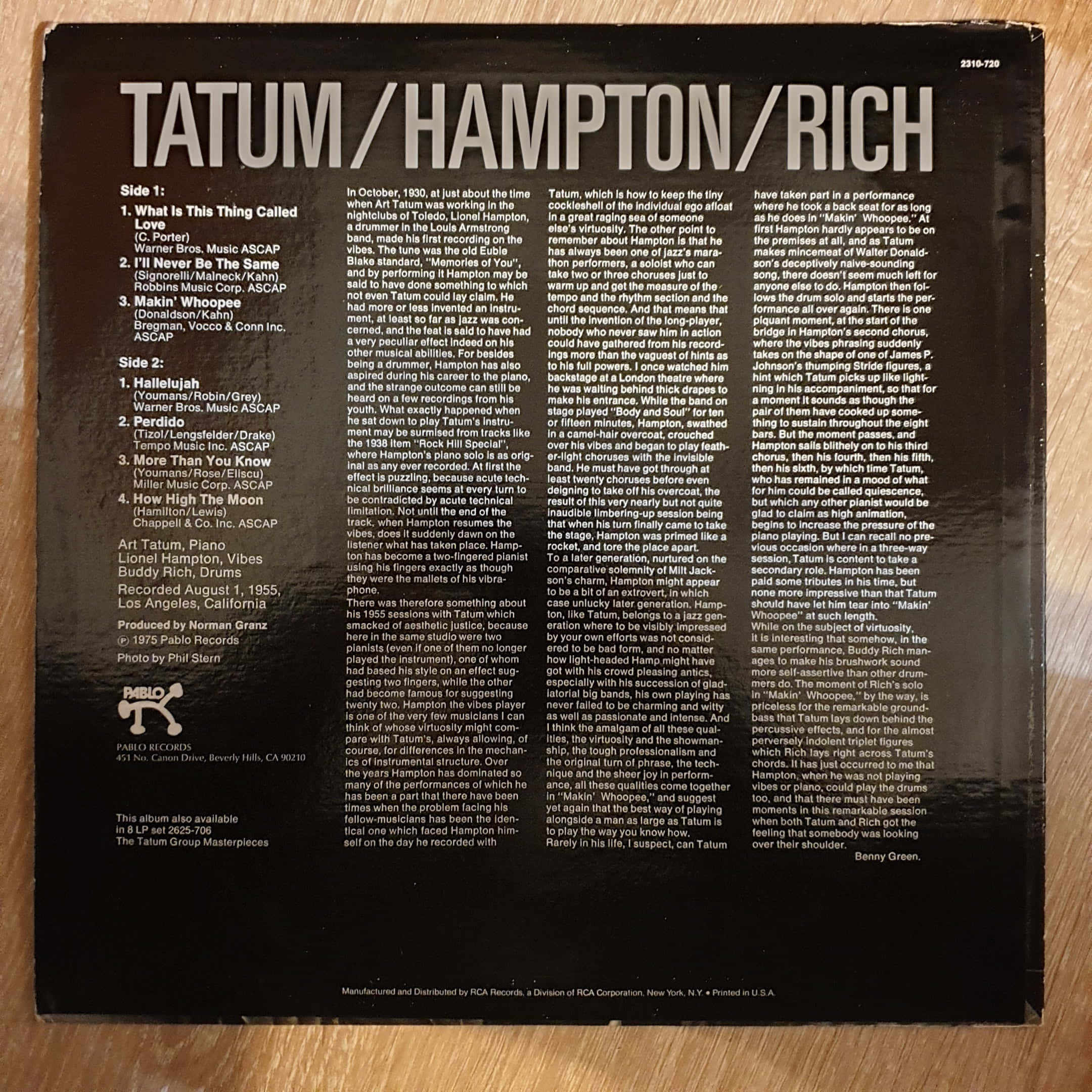 傳奇爵士 Vibraphonist Lionel Hampton 及其簽名 壁紙 — 復古黑色黑膠唱片專輯背面，白色文字詳細列出曲目列表和內頁說明，置於木質表面上。