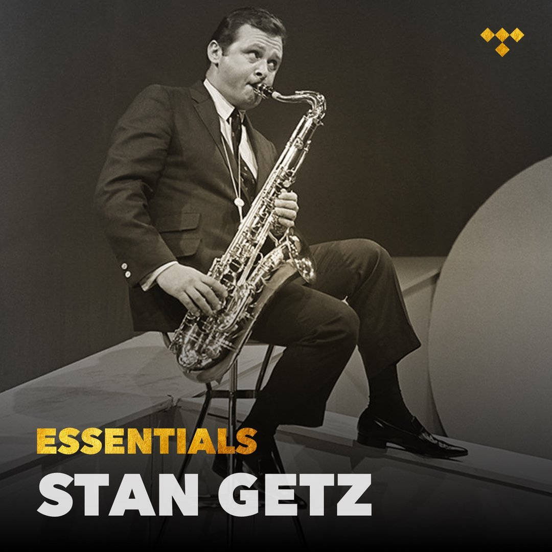 傳奇爵士樂手 Stan Getz 與他的標誌性薩克斯風 壁紙 — 一位身穿西裝的爵士薩克斯風手在極簡工作室背景下專注地演奏他的樂器。