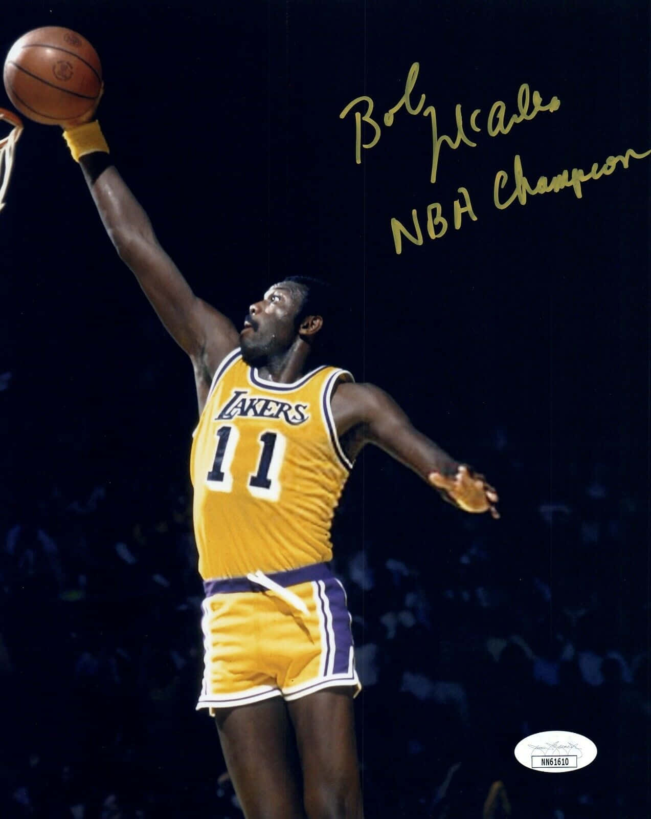 傳奇美國NBA冠軍鮑勃·麥道奧簽名照 壁紙 — Bob McAdoo 身穿黃色湖人隊11號球衣，在明亮的場館燈光下高高躍起扣籃。