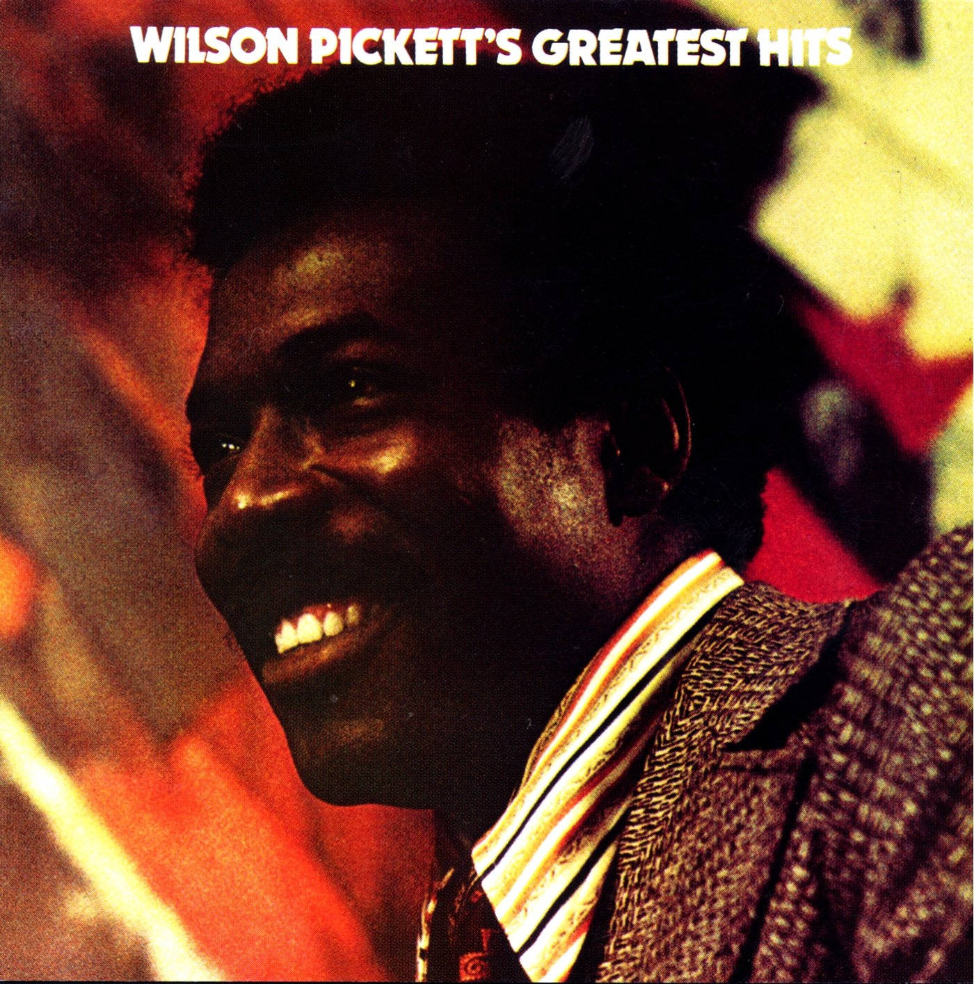 Wilson Pickett 穿著質感西裝在熾熱背景前微笑。