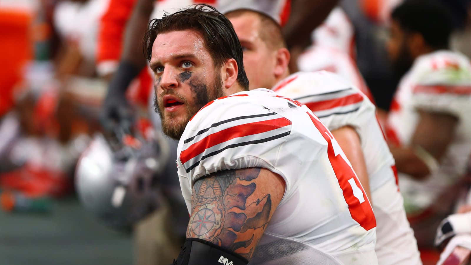 傳奇美式足球 Offensive Tackle 達克·泰勒 壁紙 — 一名美式足球員在比賽中臉上塗有顏料和紋身，近距離地凝視鏡頭外。