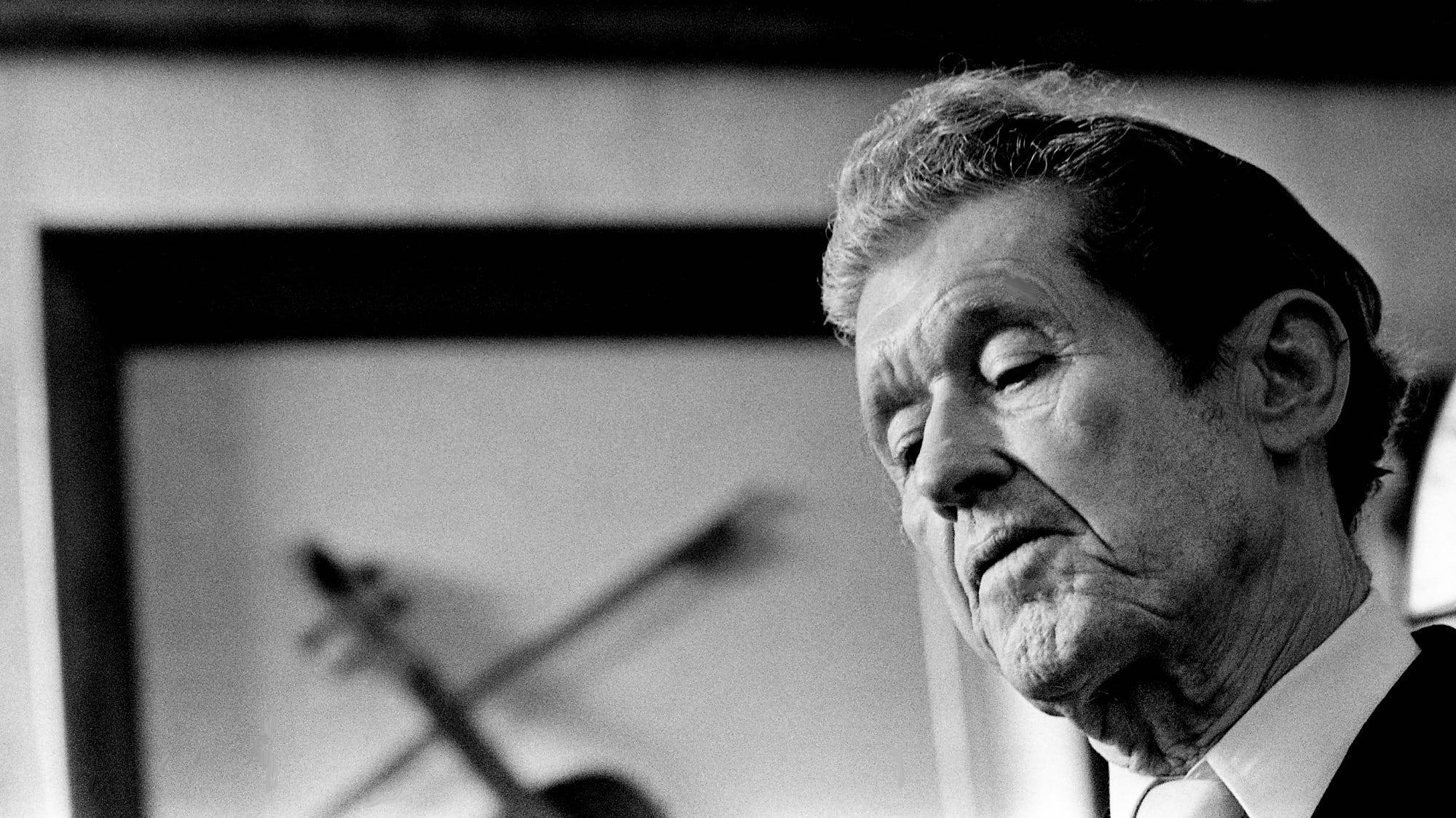 傳奇鄉村音樂巨星 Roy Acuff 黑白肖像 壁紙 — 一位身穿西裝的長者的黑白肖像，背景有模糊的小提琴。