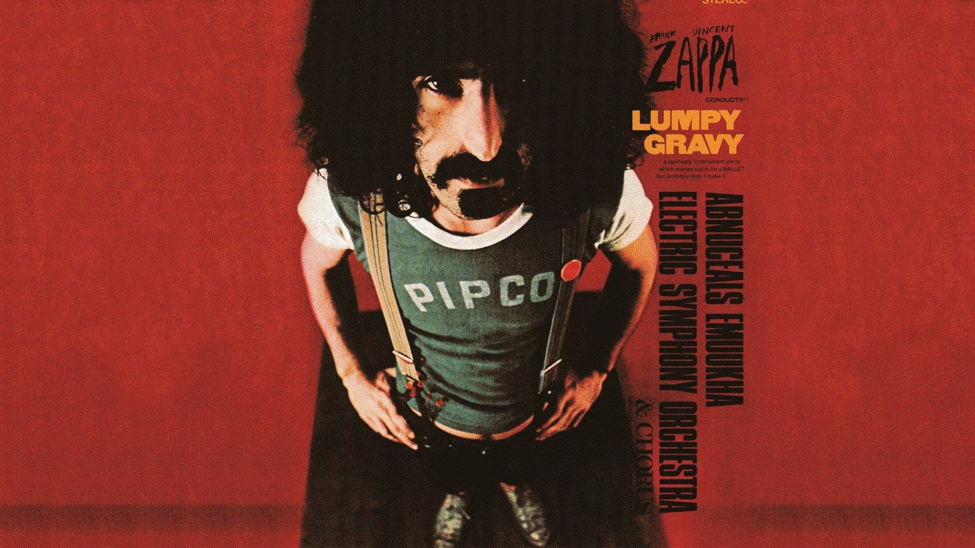 Frank Zappa 穿著綠色襯衫和吊帶褲，在紅色背景前，帶有專輯文字。