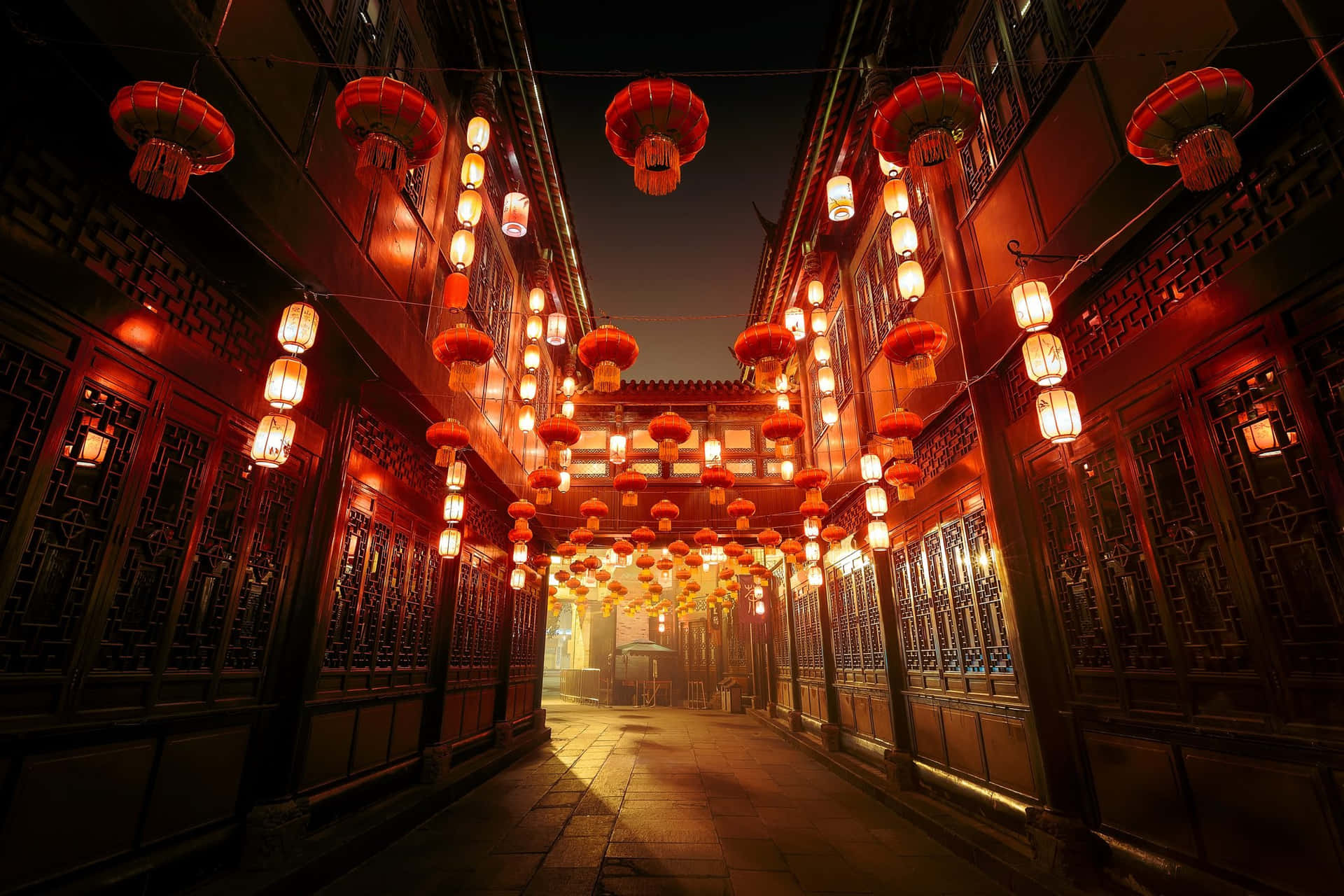 傳統中國建築與美麗景觀 壁紙 — 夜晚一條狹窄的傳統小巷，由懸掛在華麗木建築之間的發光紅燈籠照亮。