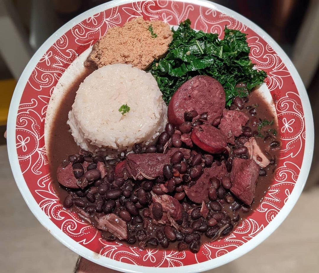 巴西黑豆燉肉菜餚，配有豆、飯和青菜，放在圖案碟子上