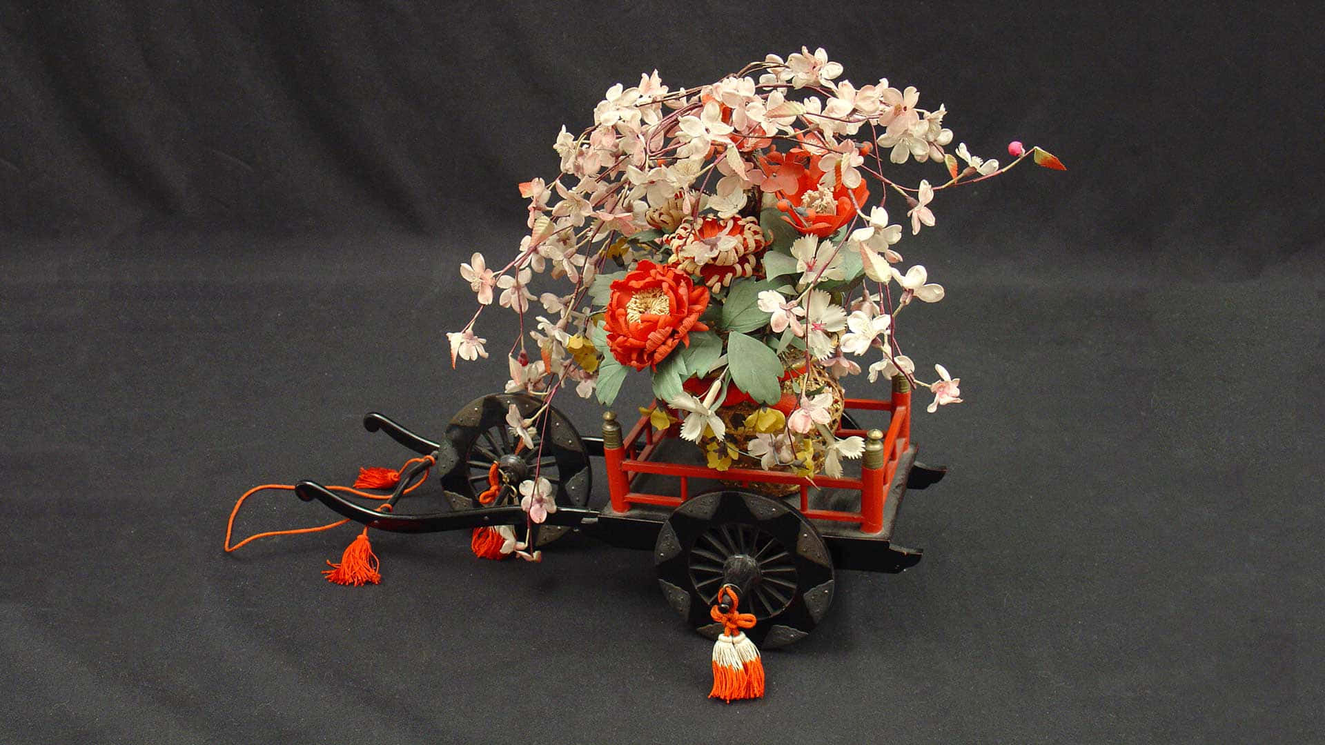 Flower Cart 桌布 壁紙 — 傳統日本手推車，在深色背景下堆滿鮮豔的紅白花朵。