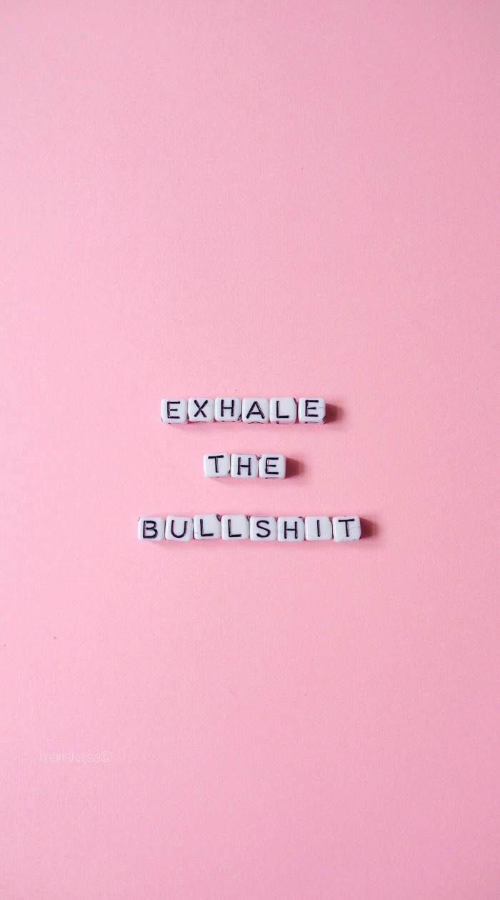 白色字母瓷磚在粉紅背景上拼出 exhale the bullshit