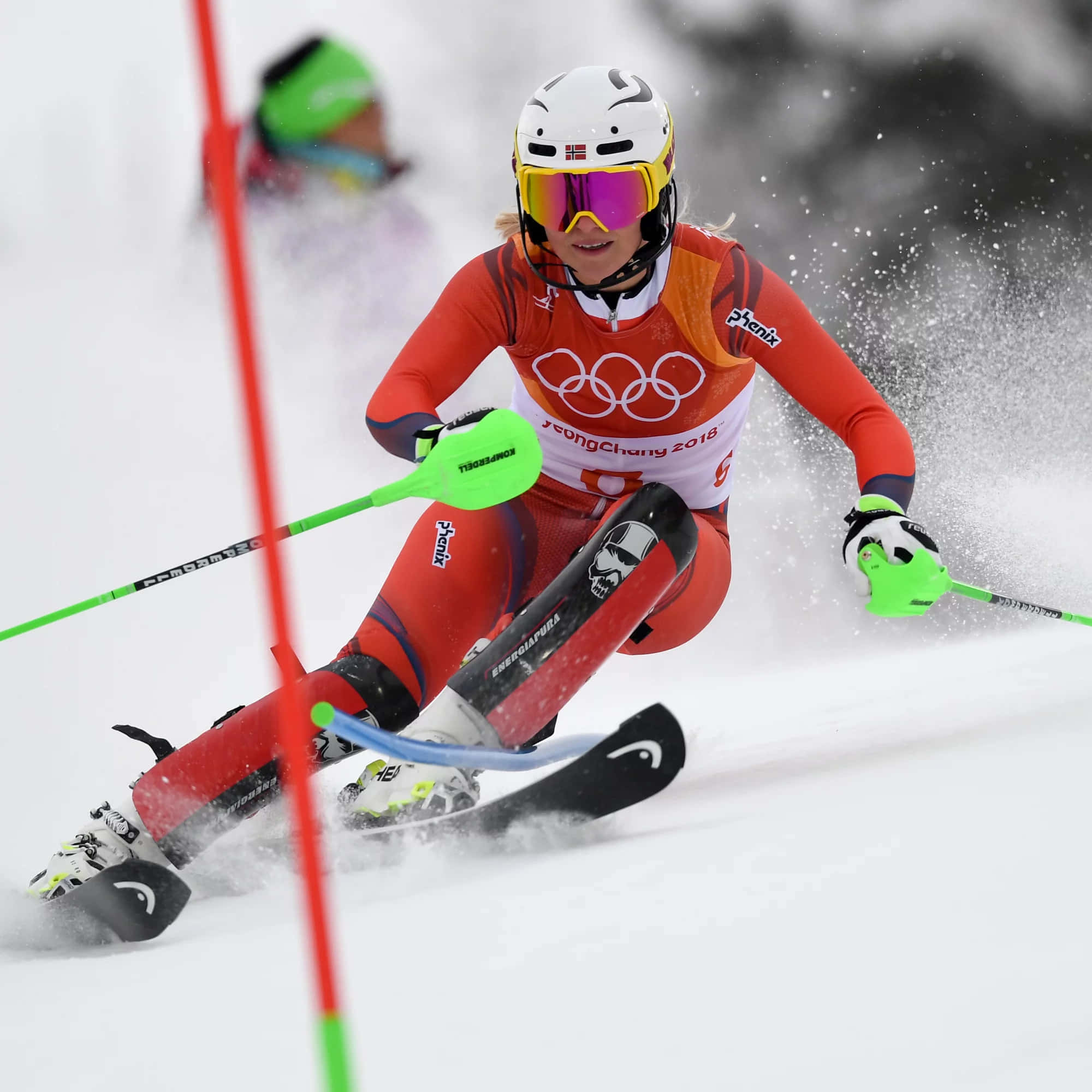 像專業選手一樣滑雪 壁紙 — 一位專注的女滑雪運動員穿著紅色奧運裝備，在競爭性下坡比賽中繞過紅色閘門在雪中滑行。