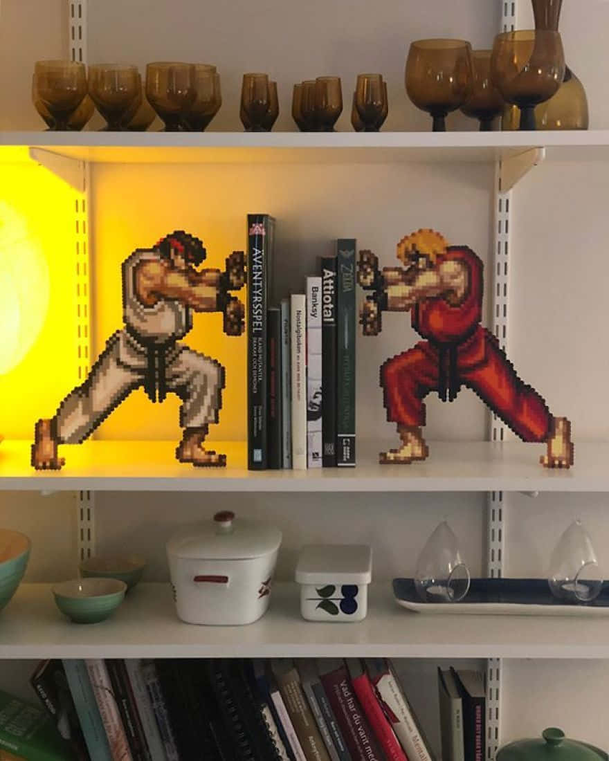 Gaming Art 桌布 壁紙 — 像素藝術戰士 Ryu 和 Ken 在一個有燈光的架子上，在書籍和琥珀色玻璃器皿中對峙。