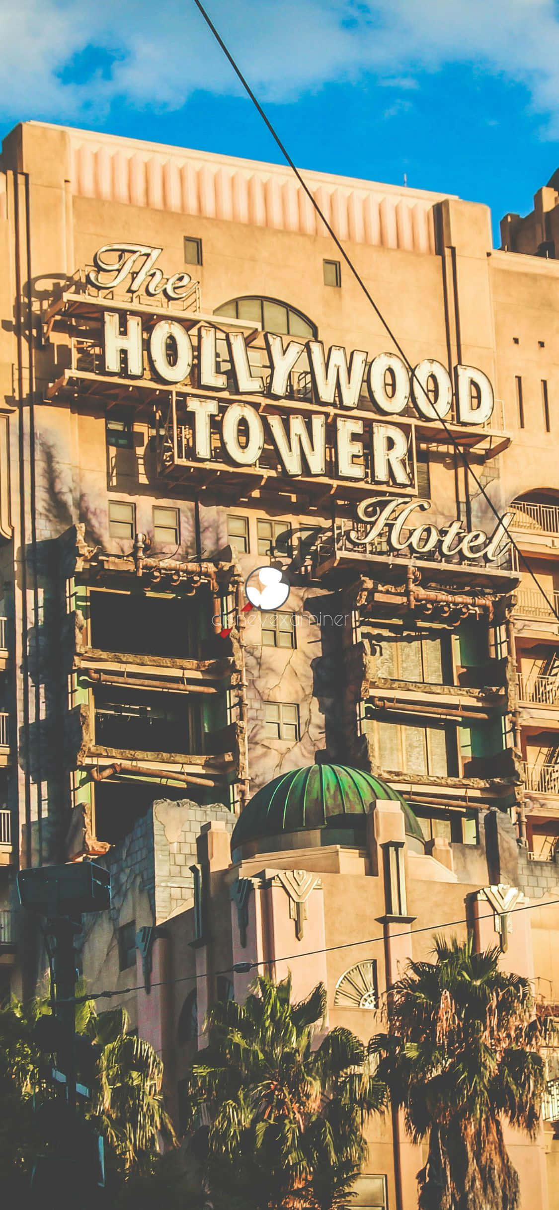 優美約塞米蒂山谷呈現在 iPhone Xs 加州背景中 壁紙 — 荷里活塔酒店在明亮的藍天下聳立，薄雲飄逸，棕櫚樹在下方搖曳。