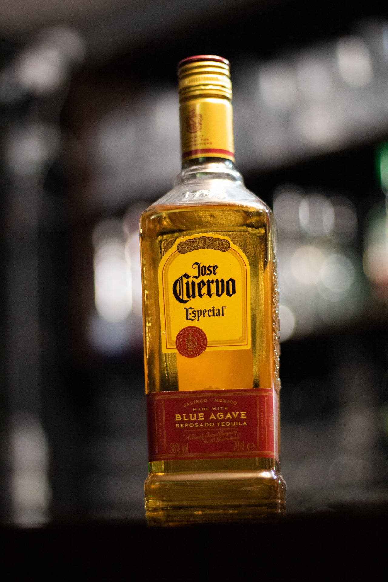 一瓶Jose Cuervo龍舌蘭酒放在酒吧上，背景有模糊的燈光。