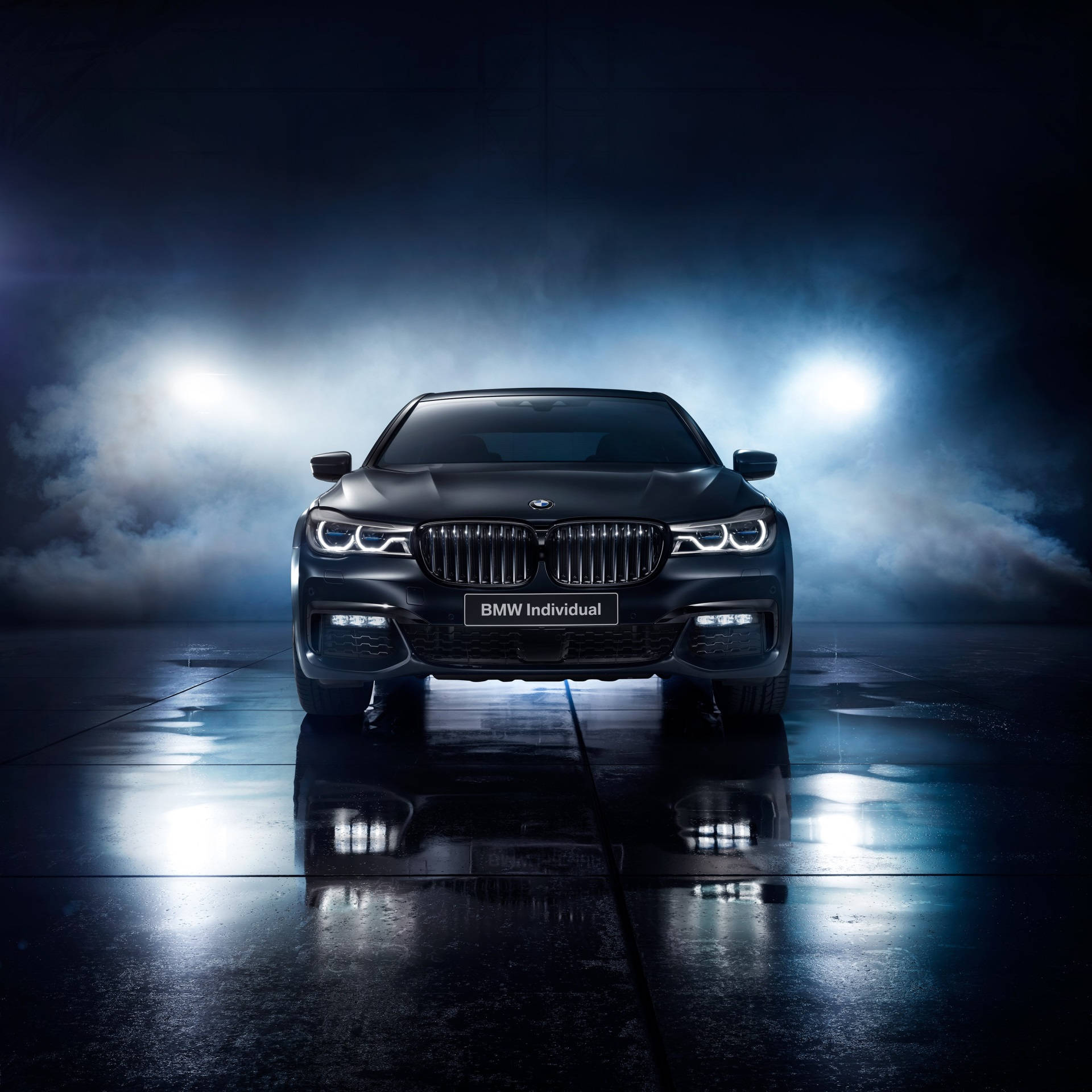 黑色BMW Individual轎車在反射性濕地板上被聚光燈照亮，伴有煙霧。