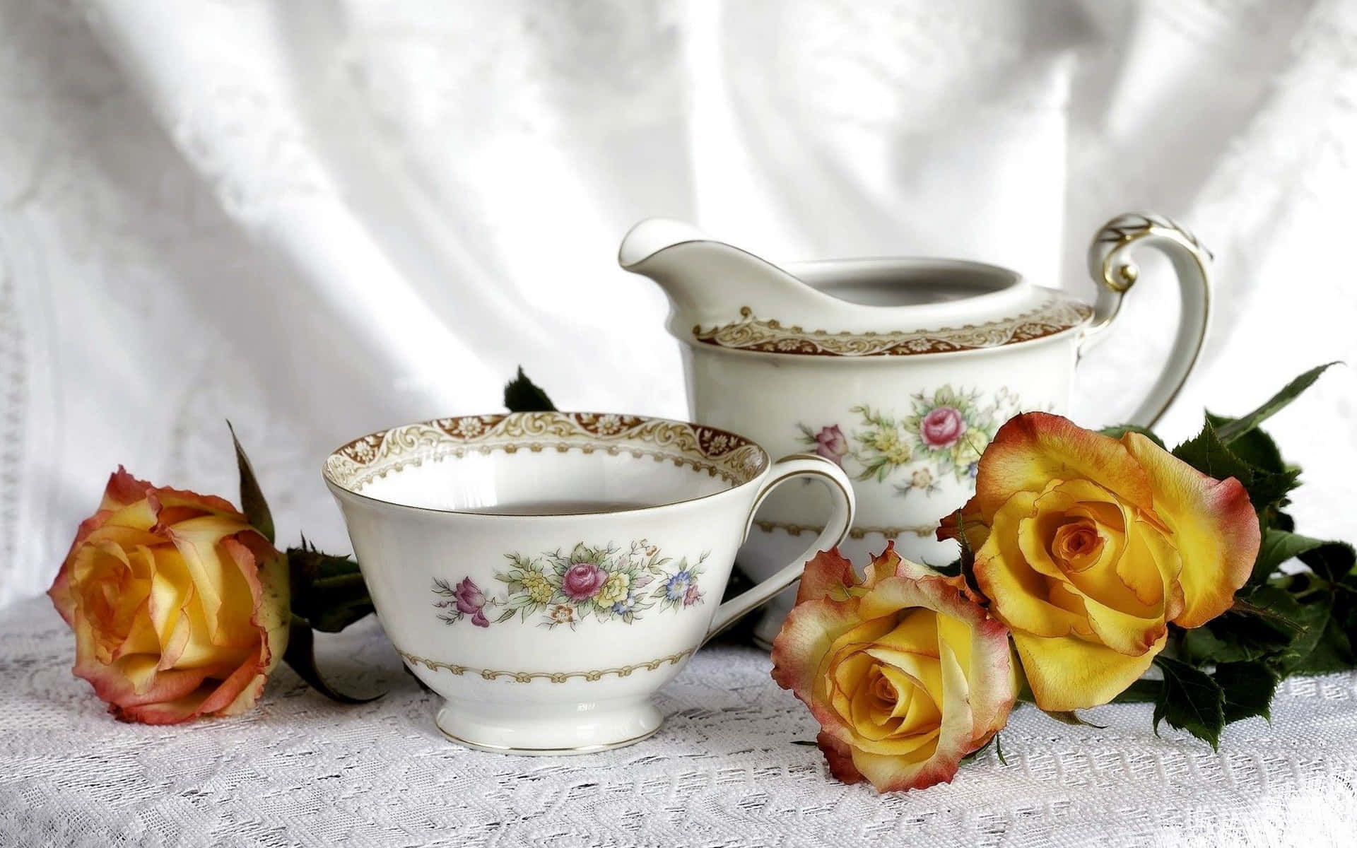 Floral Tea 桌布 壁紙 — 優雅嘅復古瓷器茶具套裝，飾有花卉圖案，擺喺蕾絲枱布上，旁邊係鮮豔嘅黃玫瑰。