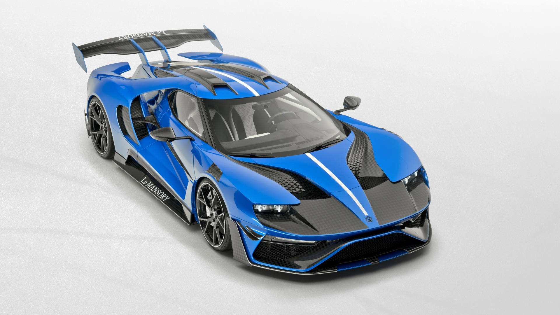 優雅強勁的 Mansory 福特 GT 壁紙 — 一輛引人注目的藍黑勒芒賽車，帶有碳纖維飾邊和大型尾翼，在攝影棚內拍攝。