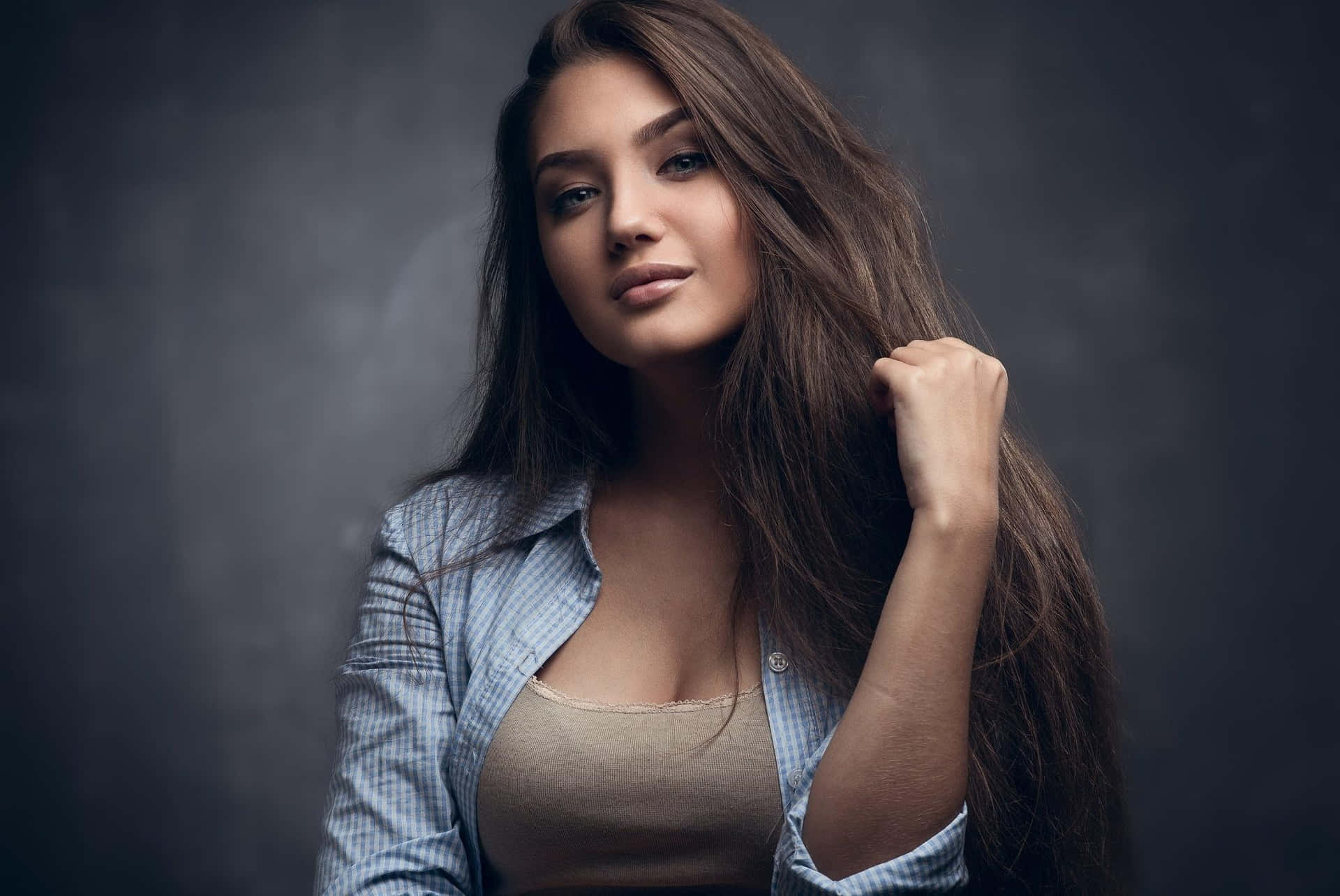 一位長棕髮女性在攝影棚中穿著藍色襯衫。