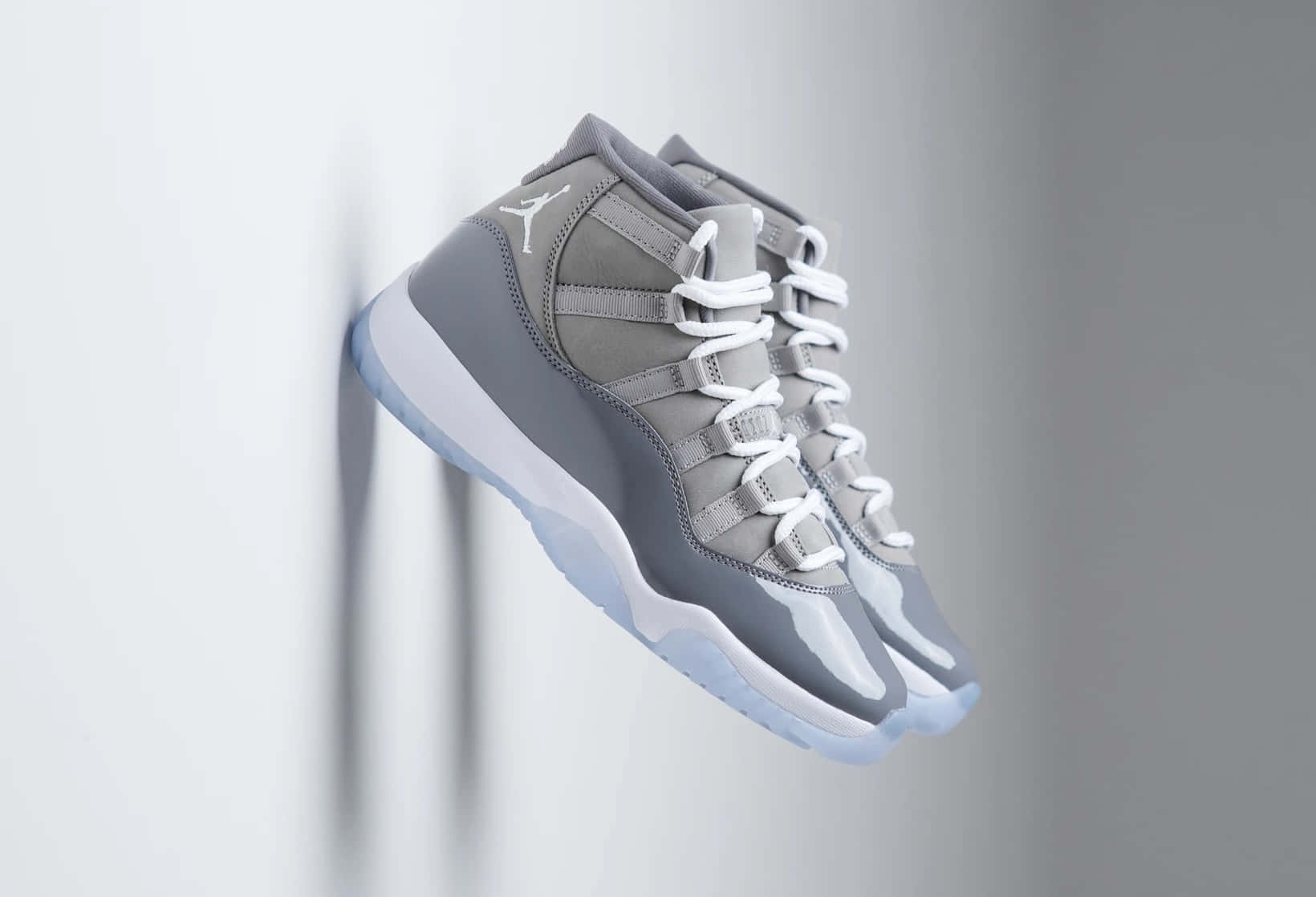 灰色Jordan 11運動鞋懸掛在半空中，背景為灰色牆壁。