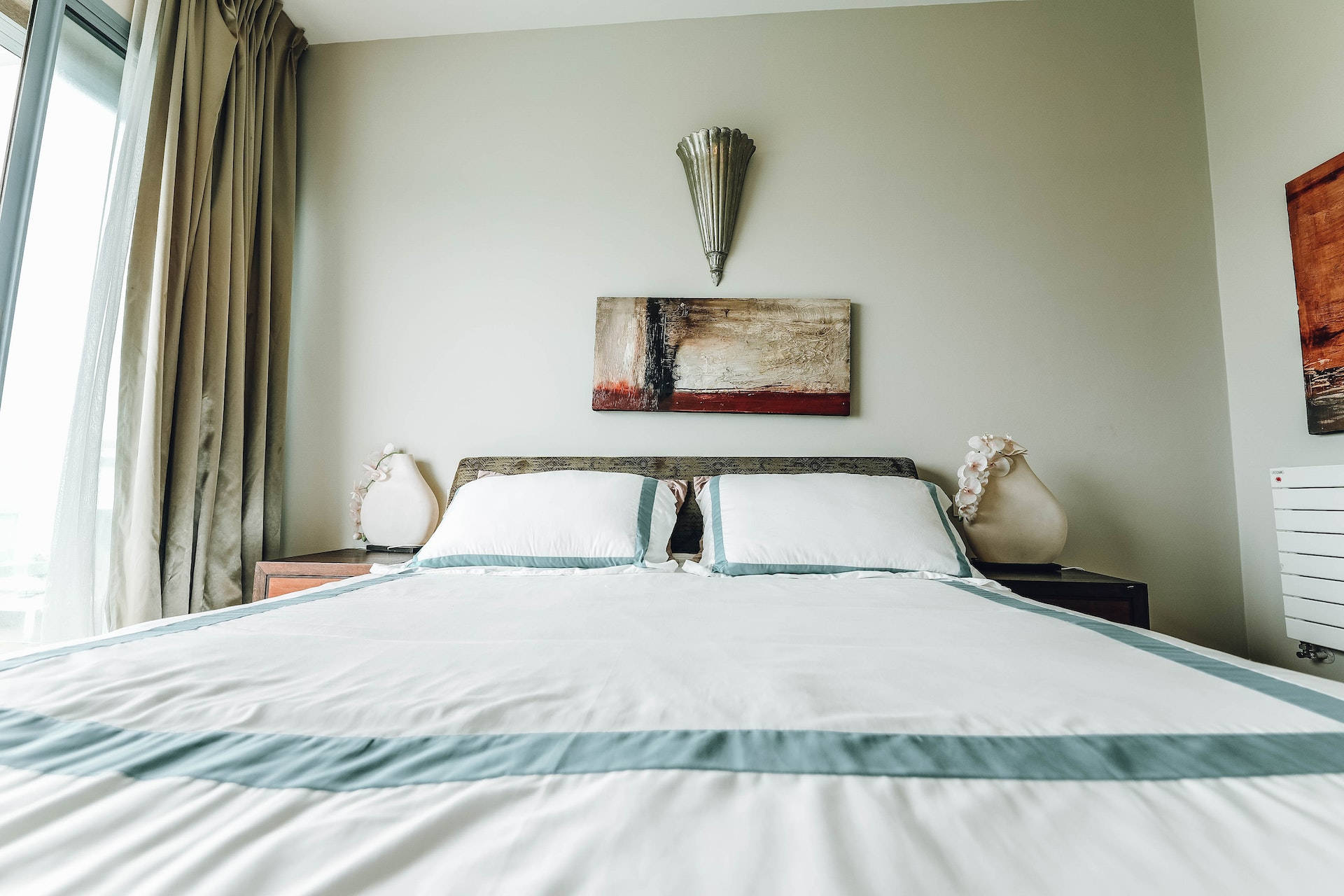 現代臥室，配有鋪好的床和帶窗簾的大窗戶。