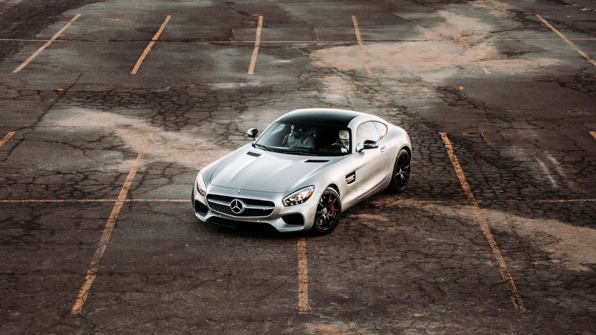 銀色 Mercedes-AMG GT 跑車停泊在一個風化的停車場。
