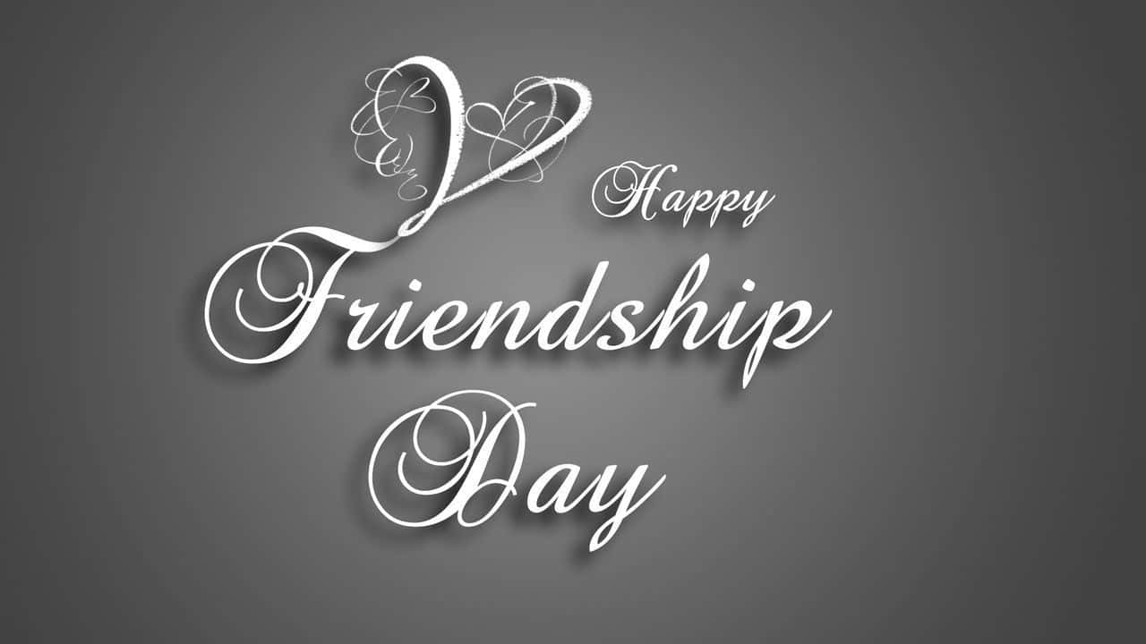 Friendship Day 桌布 壁紙 — 優雅的白色草書文字寫著「Happy Friendship Day」，並帶有心形圖案，背景為柔和的灰色漸變。