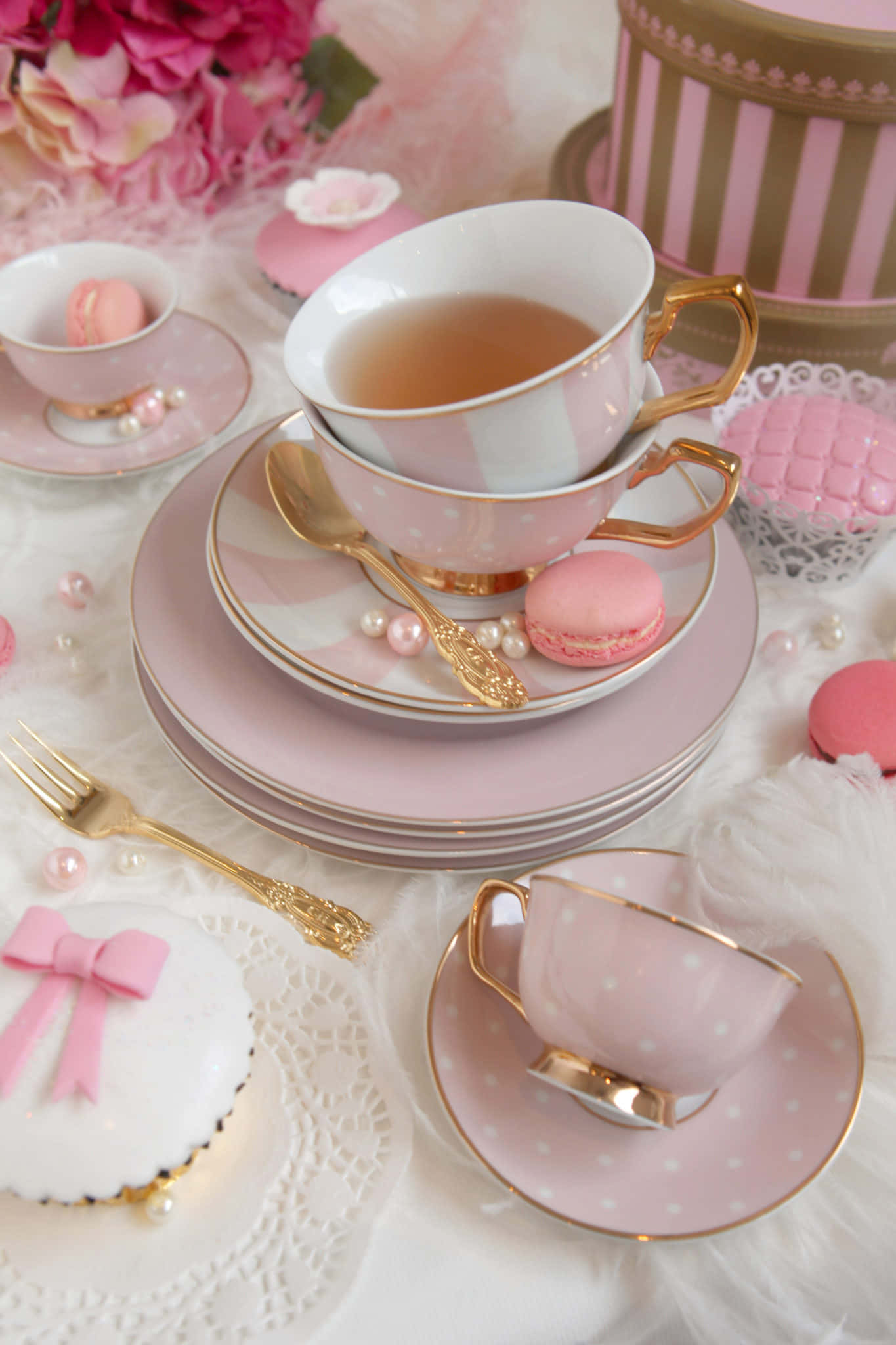 Pink Tea 桌布 壁紙 — 優雅的粉紅與金色茶具套裝，搭配馬卡龍和珍珠，擺放在蓬鬆的白色表面上。